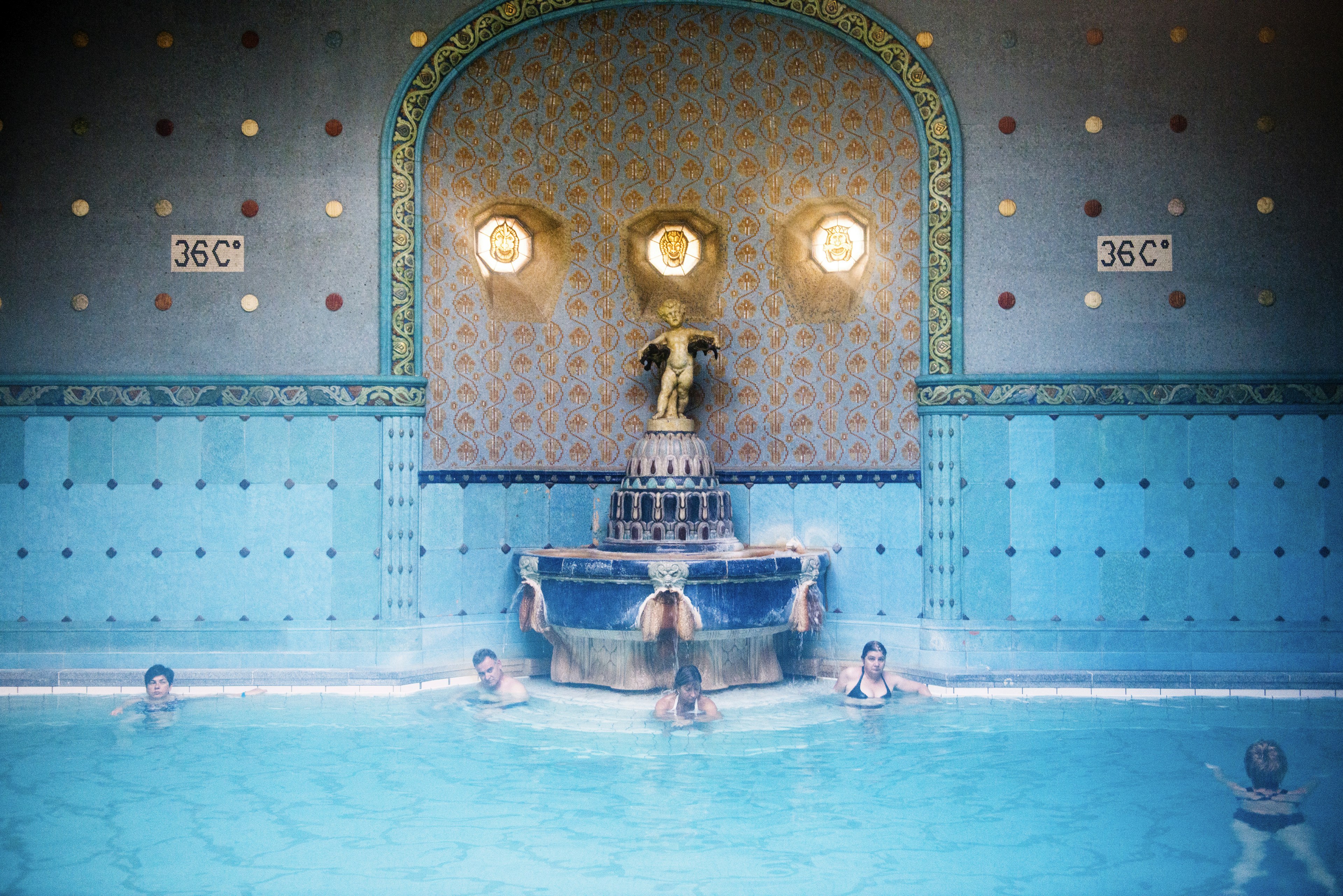 People sitting beside Art Nouveau fountain at Gellert spa.