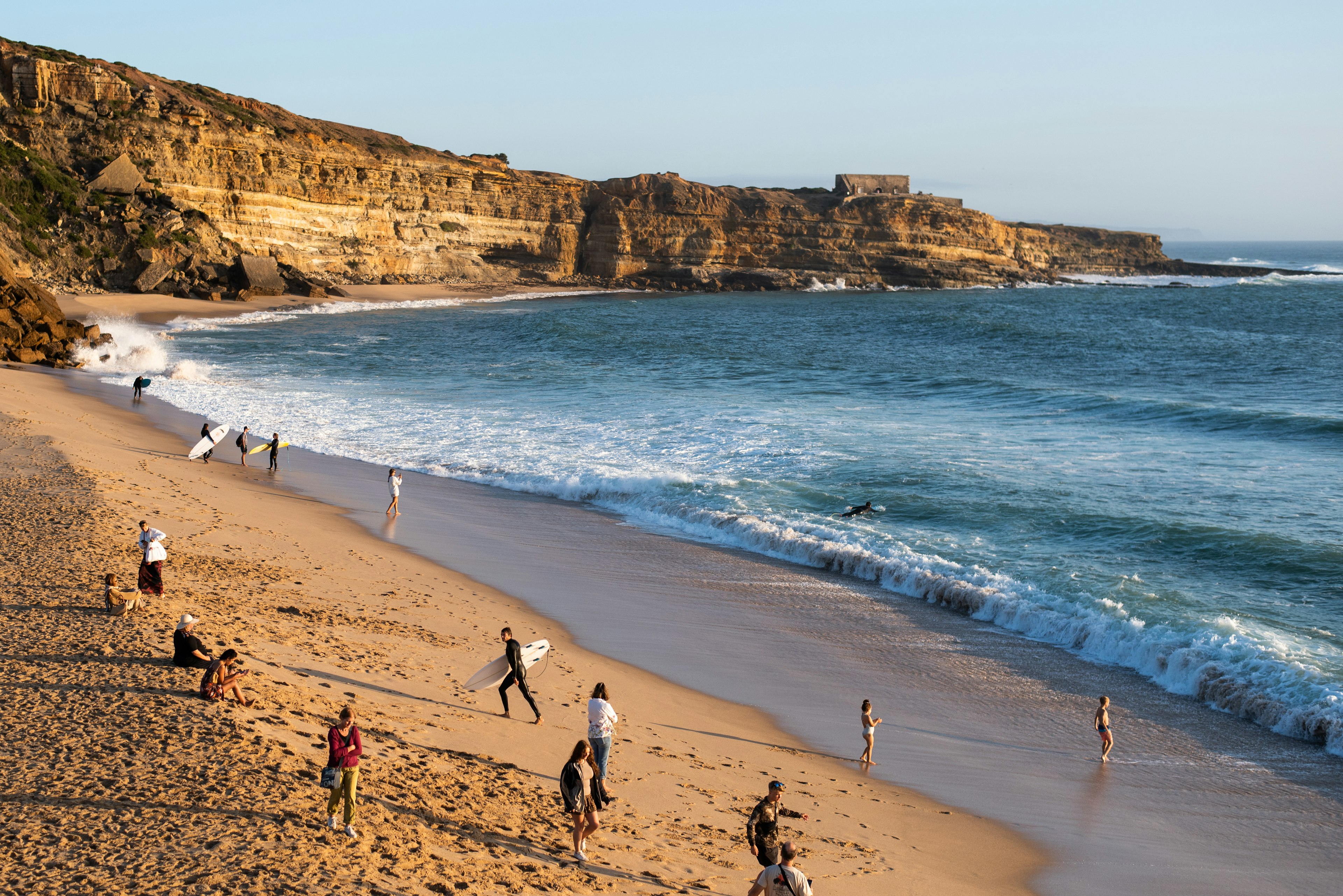 Beachgoers and surfers along Portugal's coast.