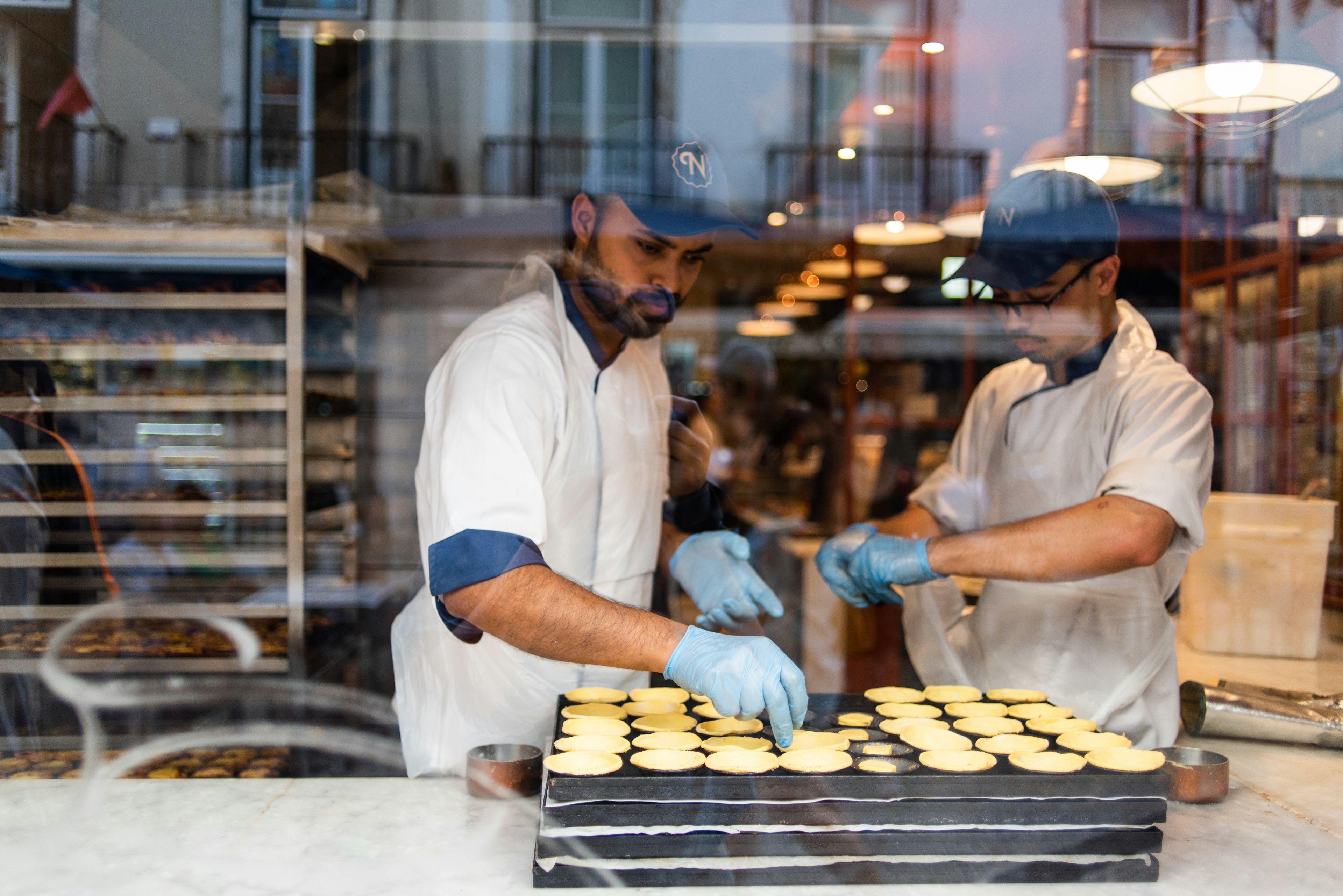 Two bakers preparing a tray of Pastel de nata in Baixa, Lisbon