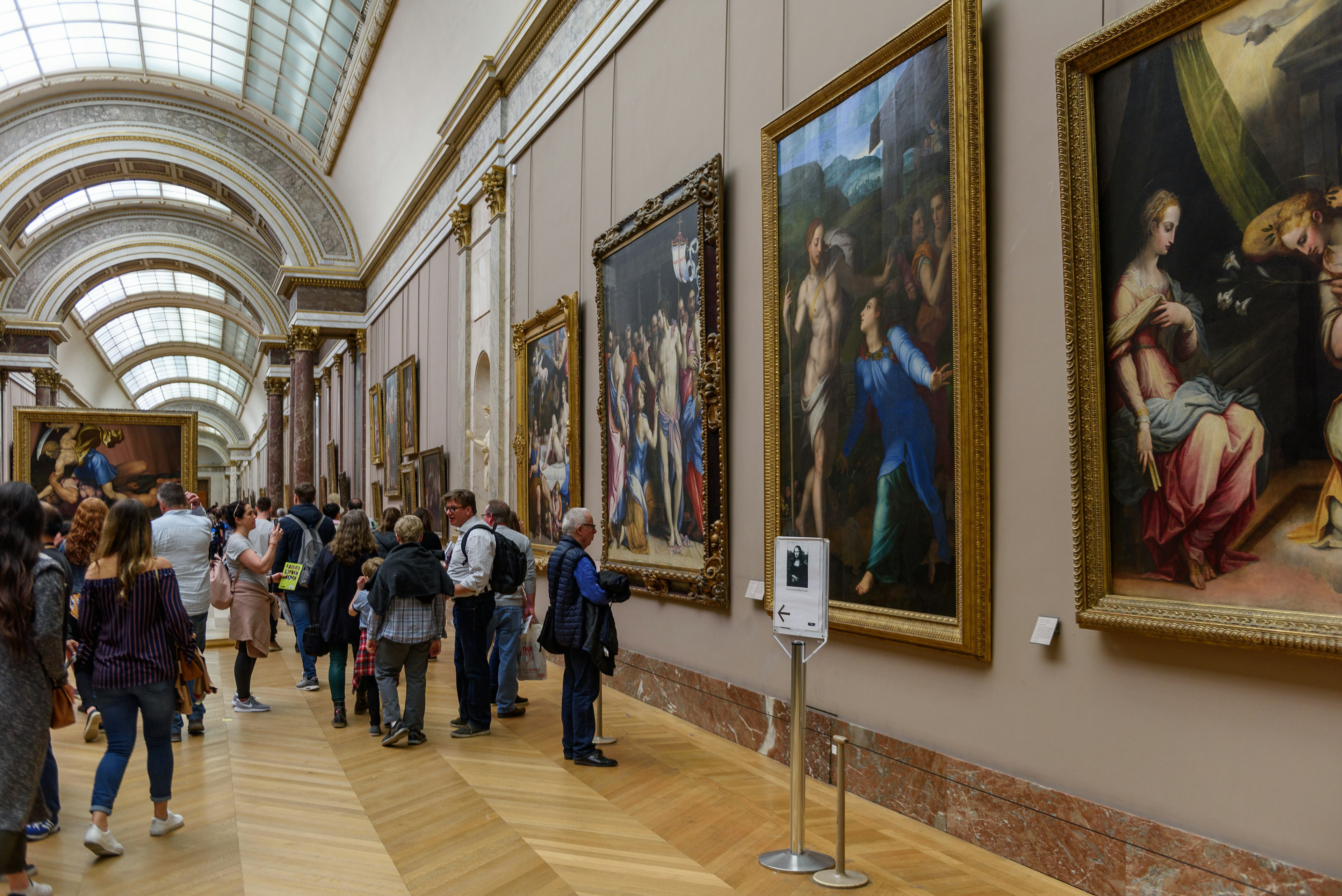 Unidentified people in the Grande Gallery in Louvre, the world's largest art museum and a historic monument in Paris, France