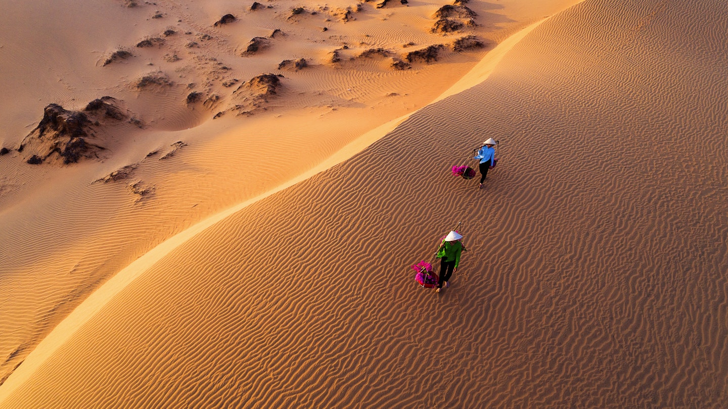 Vietnam Dec2017: aerial view of Woman carrying flower basket at sunset in Mui Ne sand dune, Vietnam  License Type: media  Download Time: 2022-05-04T03:08:48.000Z  User:   Is Editorial: Yes  purchase_order: