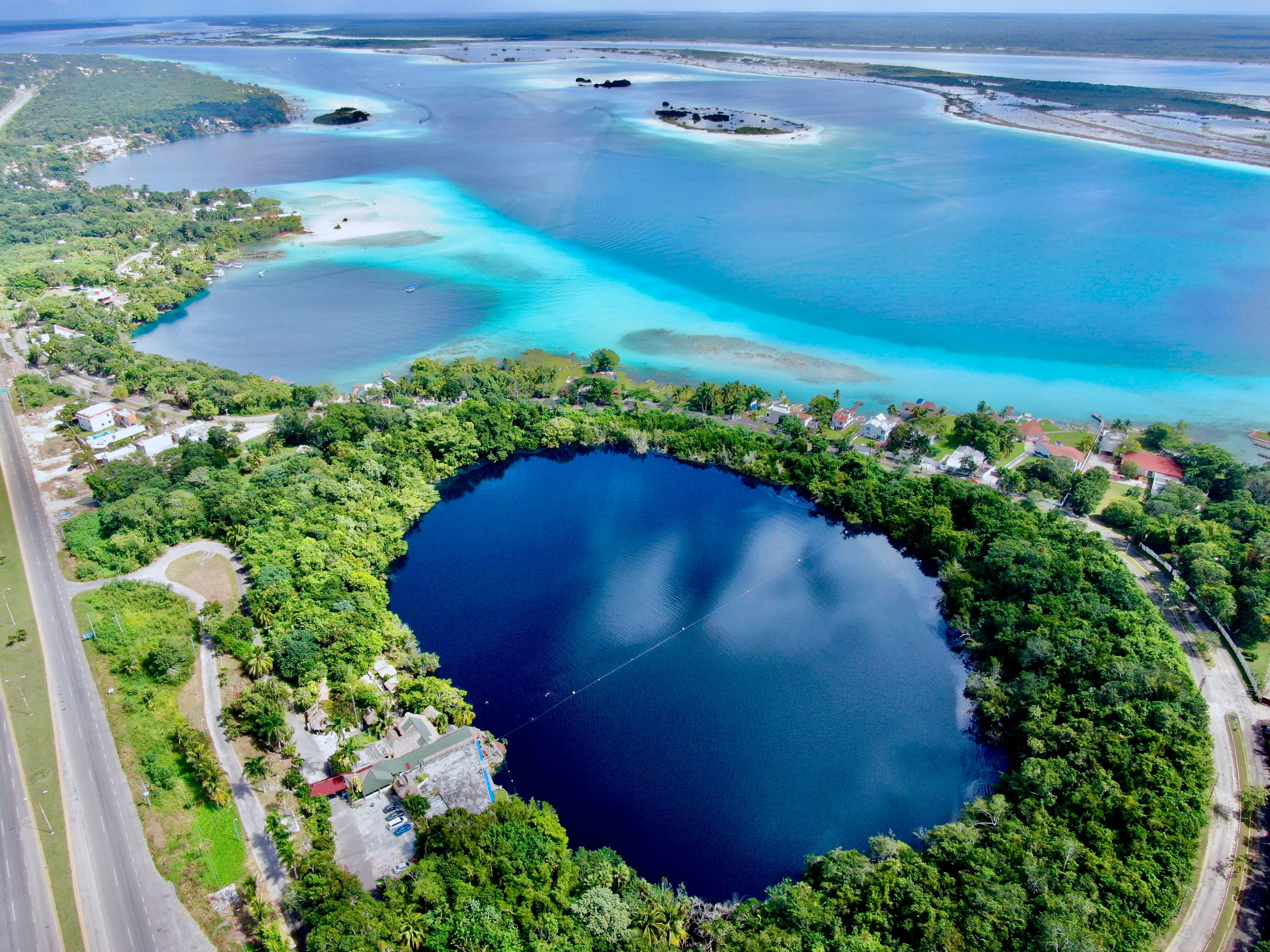 An aerial view of deep-blue Cenote Azul, next to the turquoise waters of Lake Bacalar, Quintana Roo, Mexico