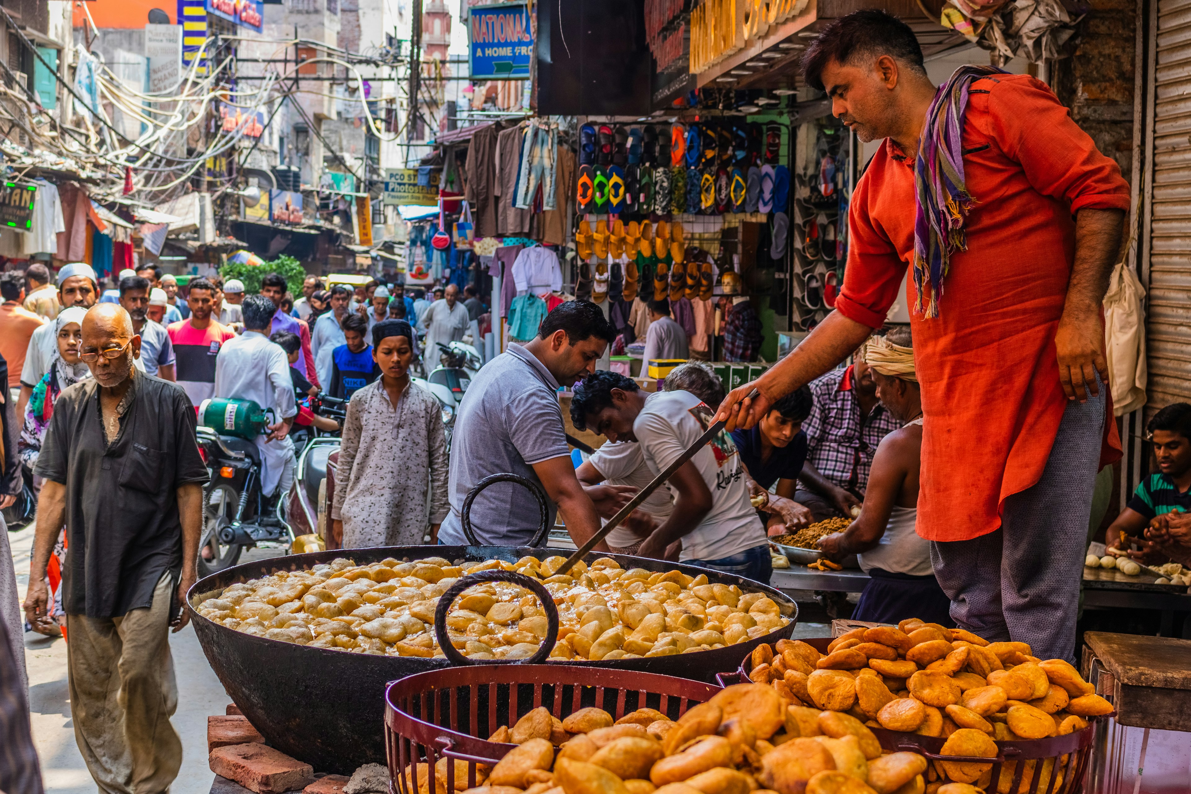 A person uses a huge ladle to fry snacks in a giant pan on the streets of old Delhi in India