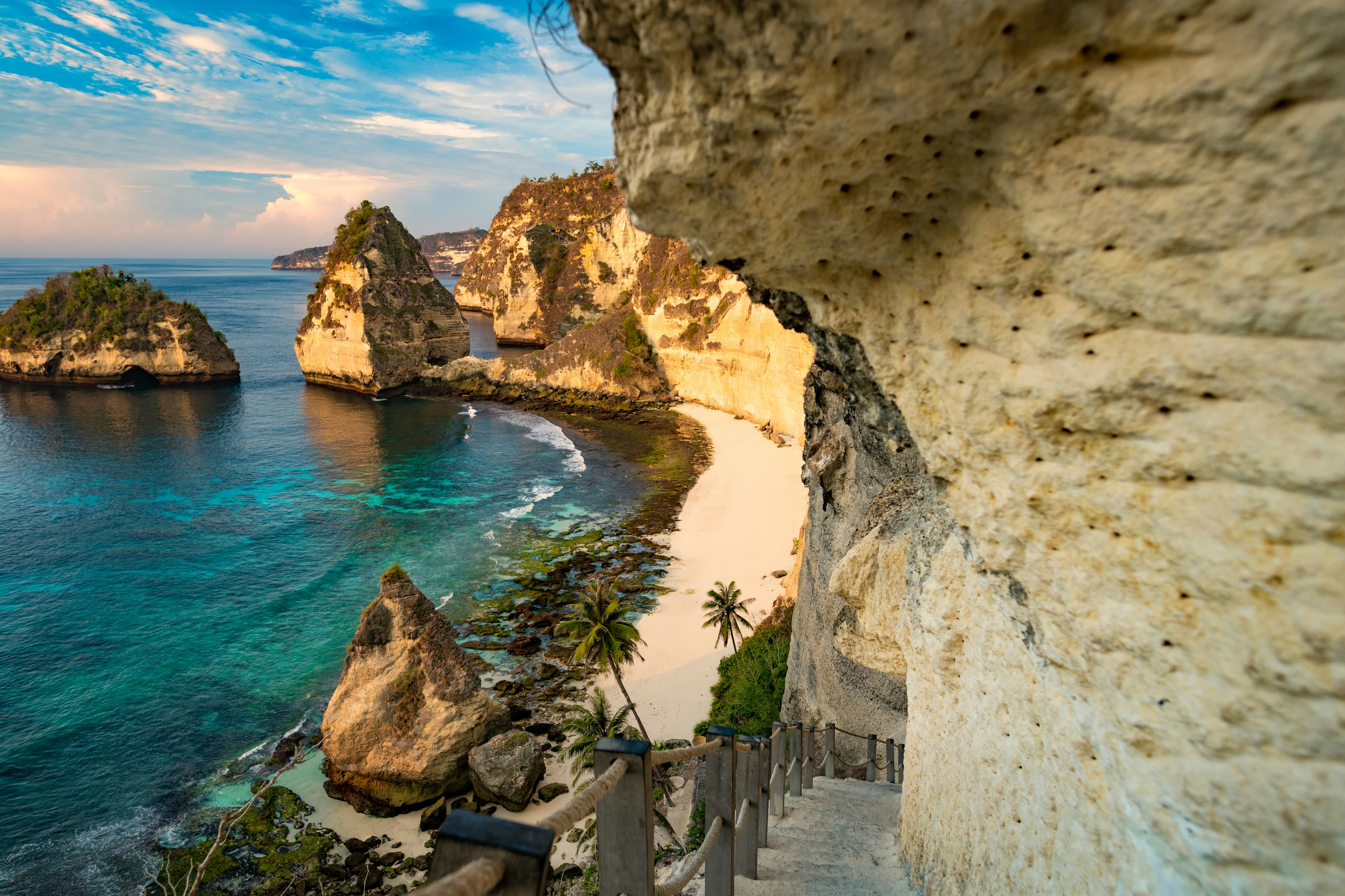 A small sandy beach in the shadow of a huge cliff