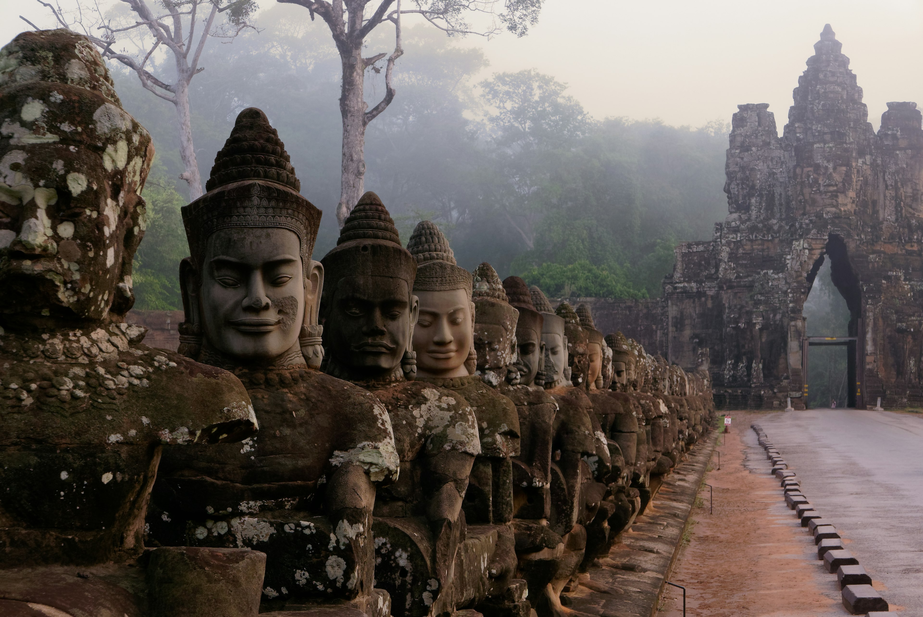 Statues of people led along a pathway to Angkor Wat, Cambodia.