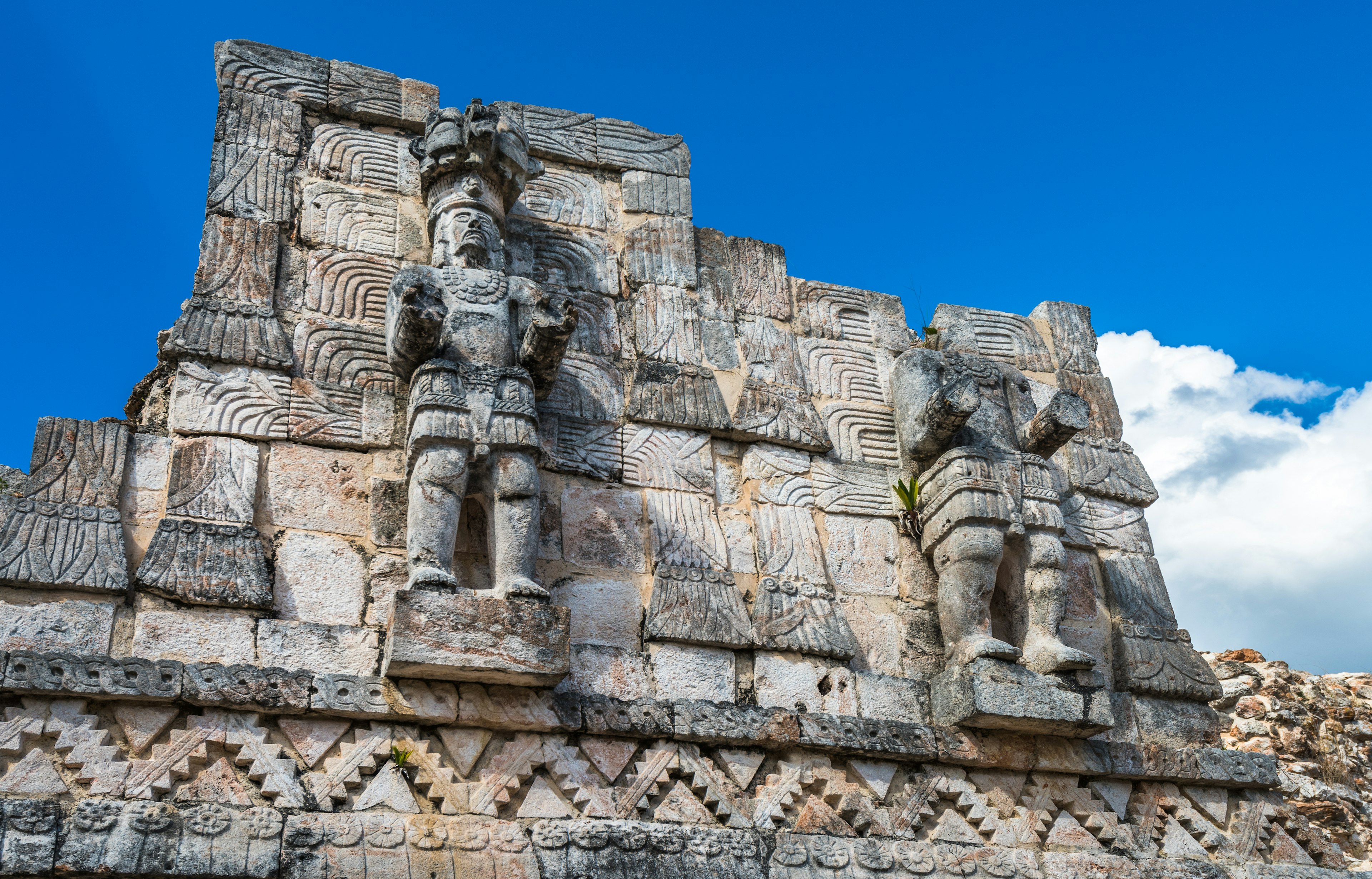 Stone reliefs of Mayan gods on the side of a pyramid