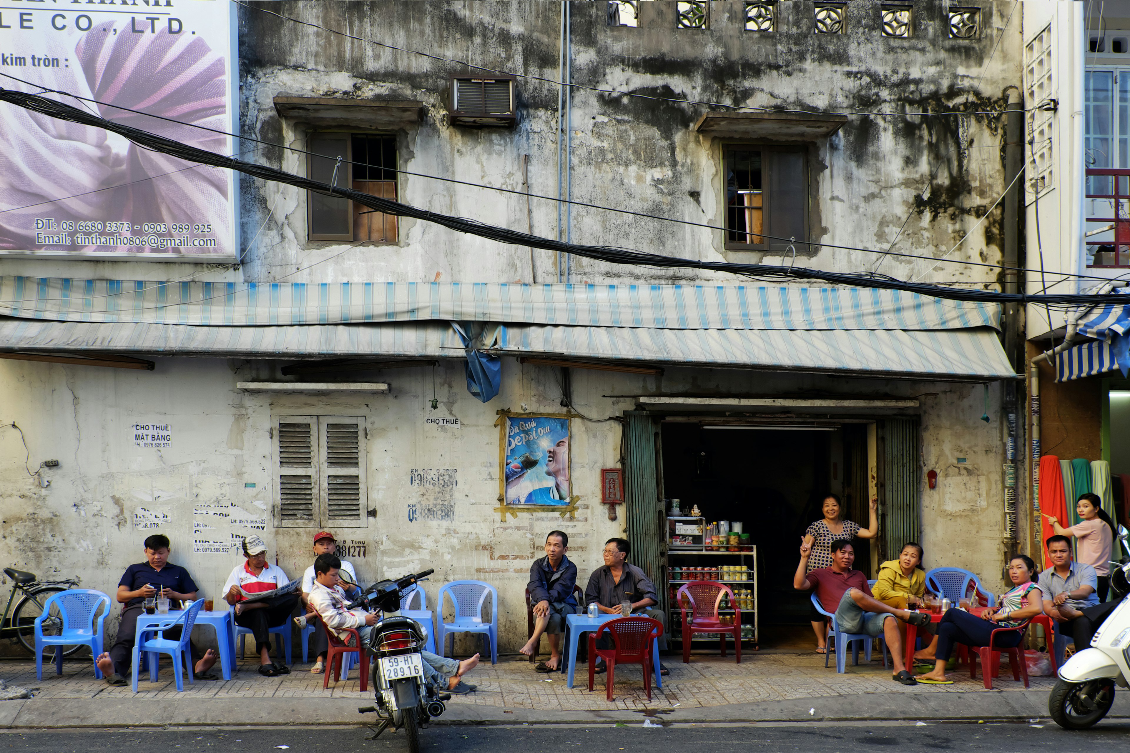 HO CHI MINH CITY, VIET NAM Group of Asian people sit at pavement coffee shop at morning, sidewalk cafeteria is Vietnamese cultural where people can chat together.