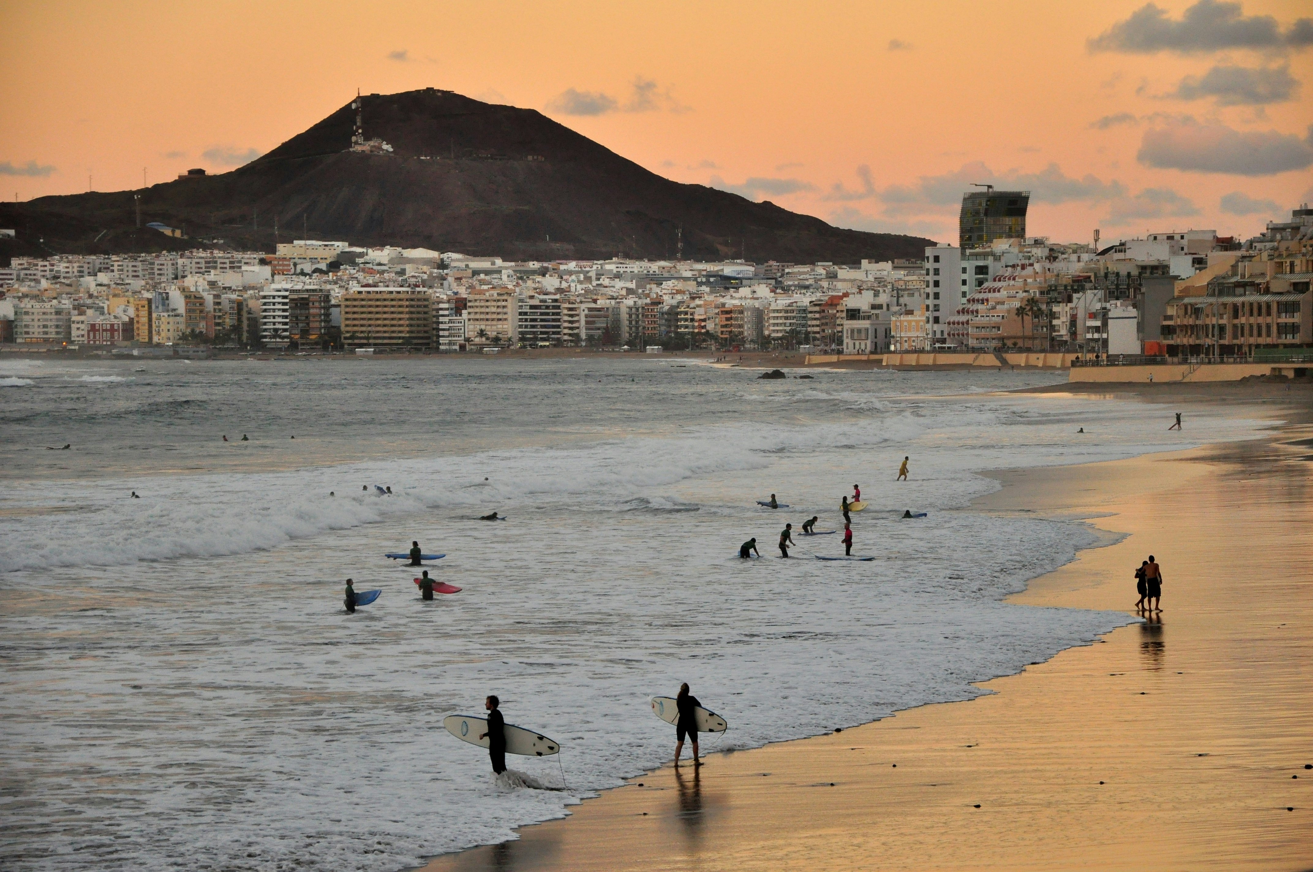 Sunset in Las Palmas de Gran Canaria. Surfers enjoying city beach.