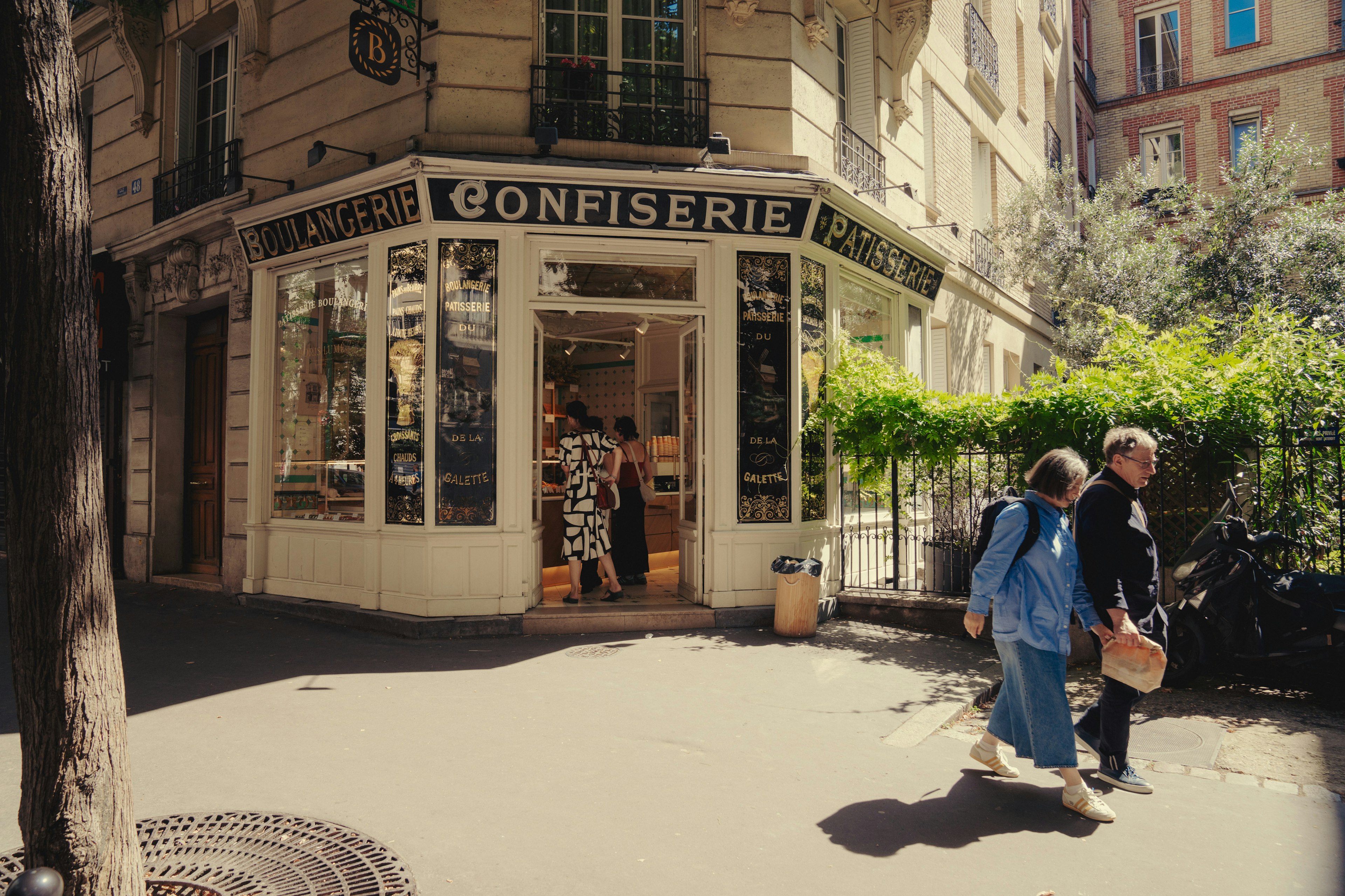 An older couple walks by a bakery in the 18th arrondissement of Paris, France