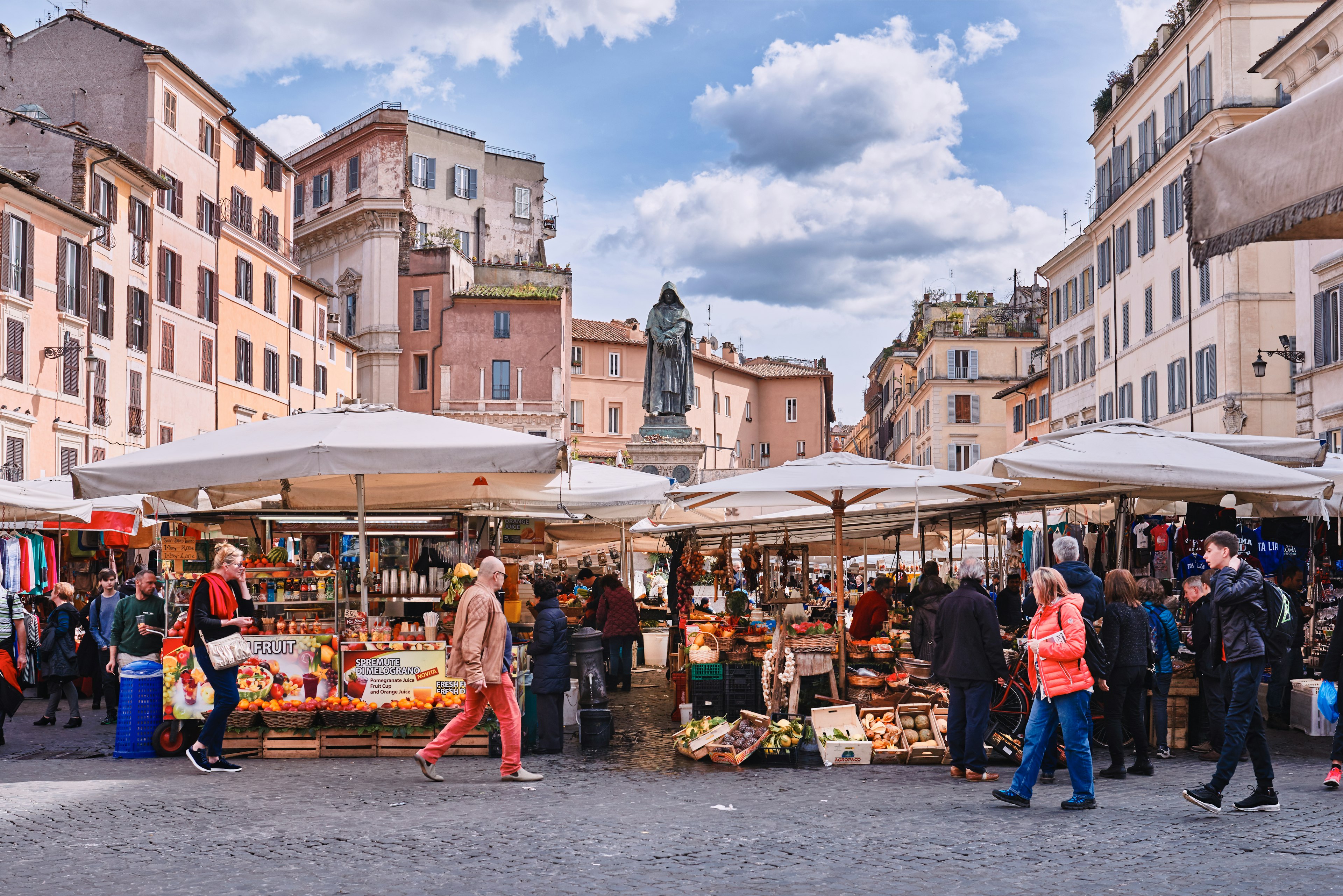 A scene of passersby in Rome, Italy walking through the traditional outdoor food market of Campo de Fiori (fields of flower).