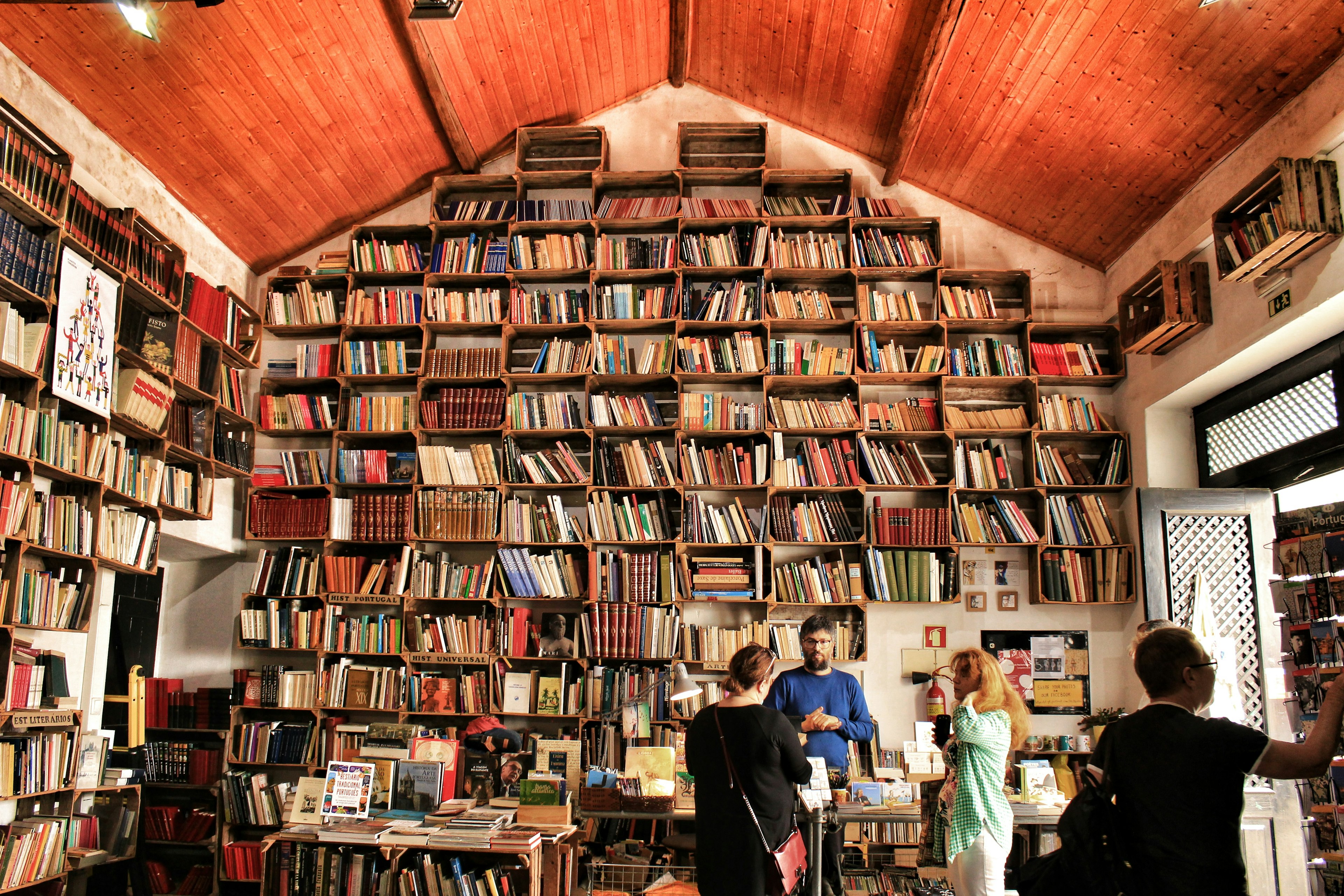 Customers in a book store, with shelves that reach all the way up to the pointed ceiling