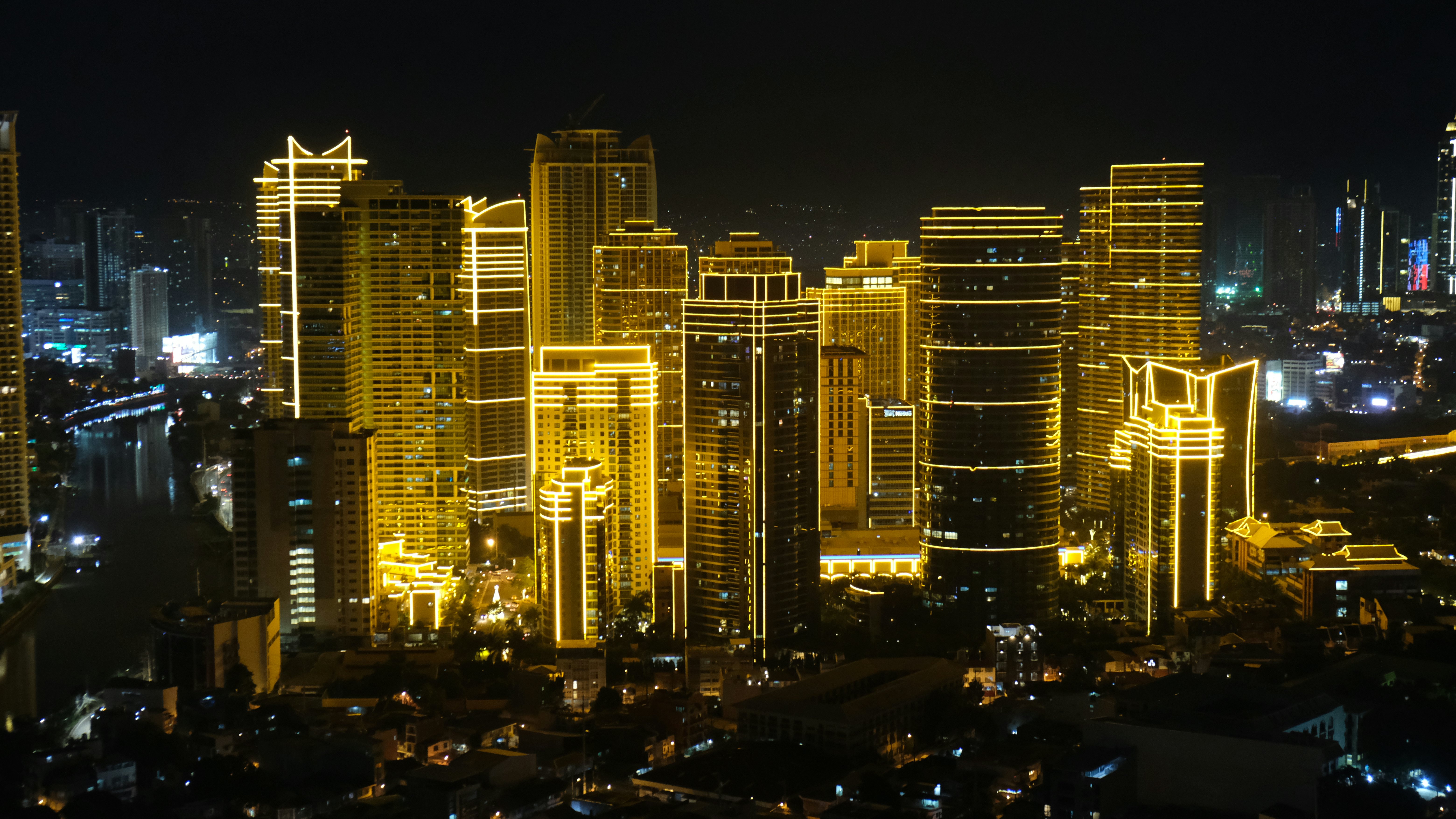 A cluster of skyscrapers is illuminated with seasonal lights, making them appear to glow gold at night