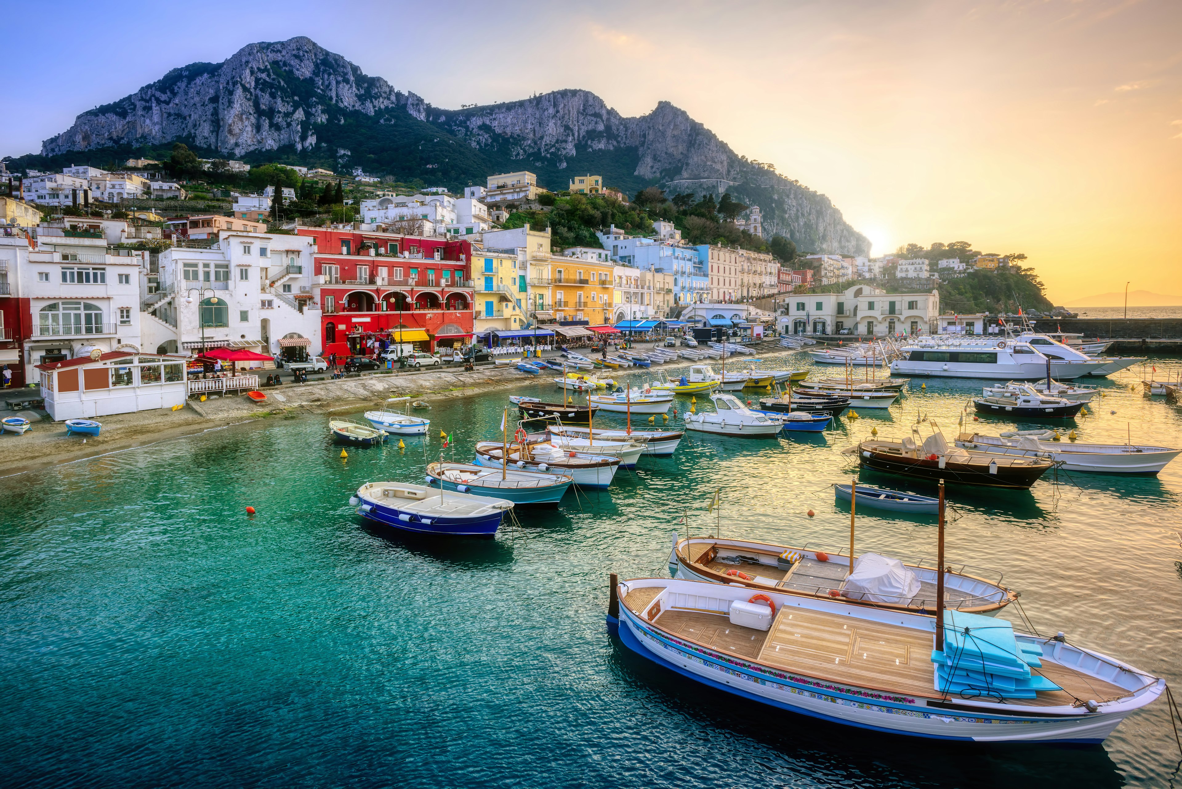 Boats docked in a small marina in front of brightly colored buildings