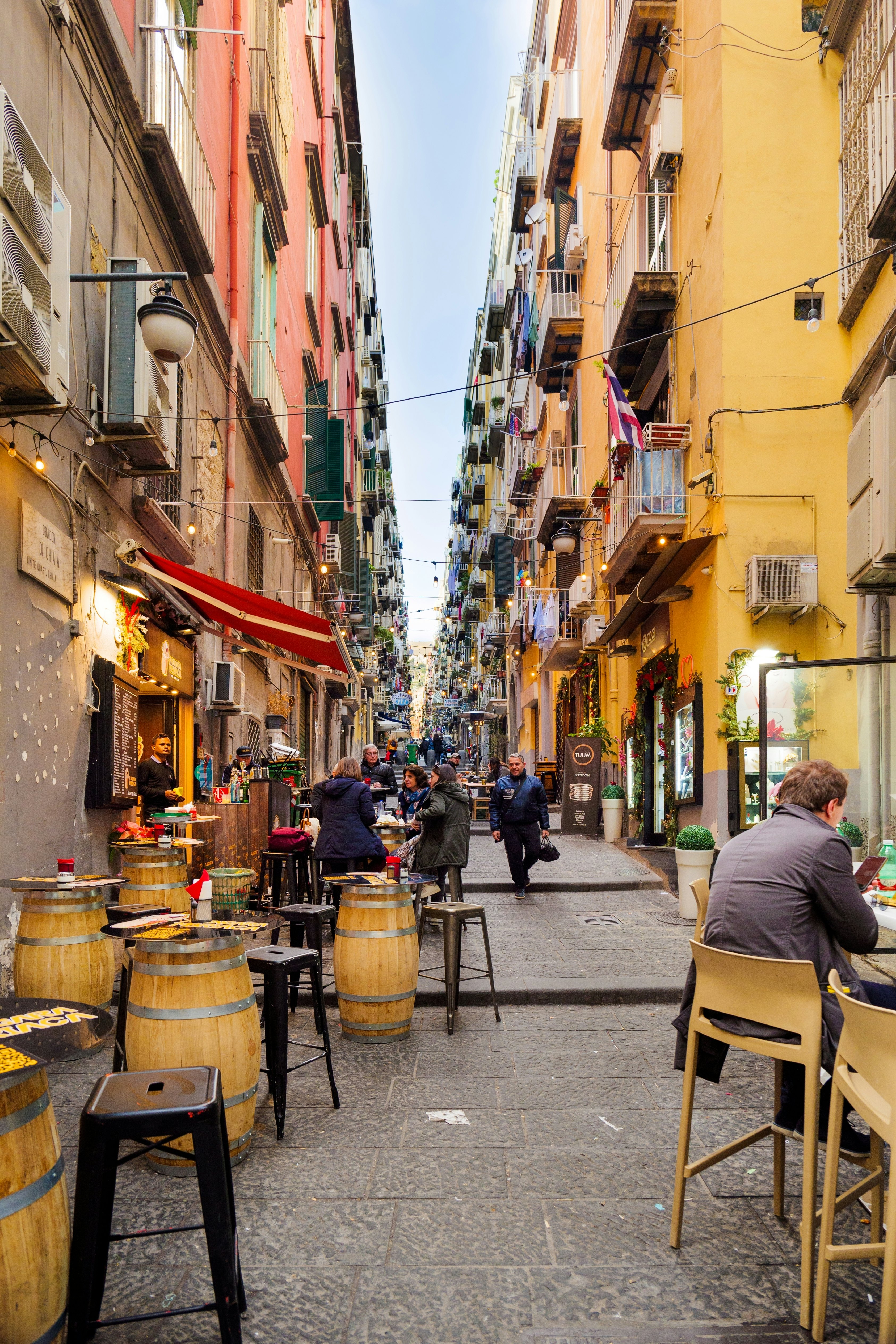 Naples, Italy. View of Gradoni di Chiaia, a narrow street that connects Via Chiaia and Corso Vittorio Emanuele. In the foreground, some people at the tables of a small pizza restaurant.