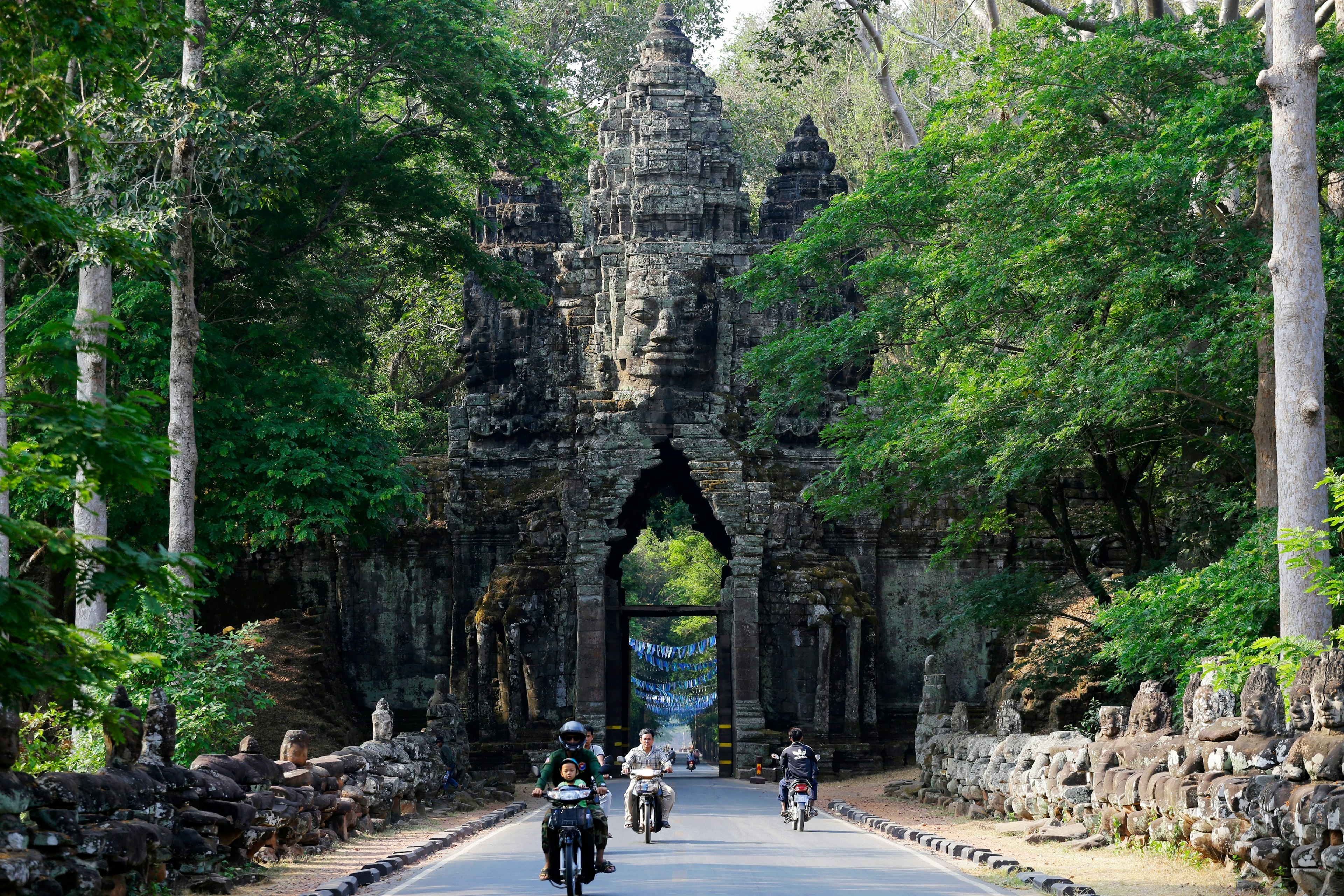 People ride motorycles through the North Gate of Angkor Thom, part of Angkor Wat complex, Cambodia