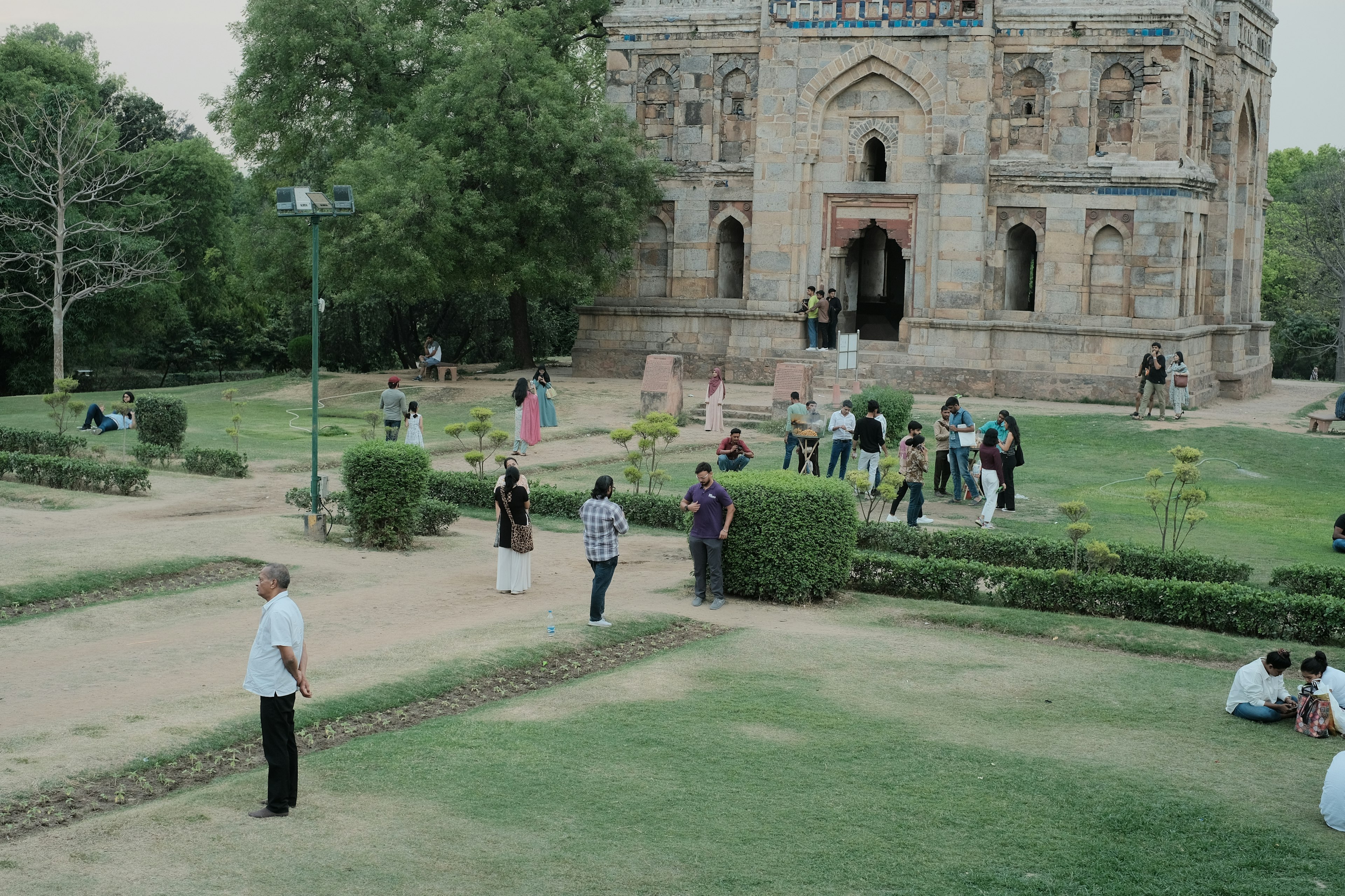 People enjoy the green lawns in front of a Mughal monument in Lodi Garden, Delhi, India