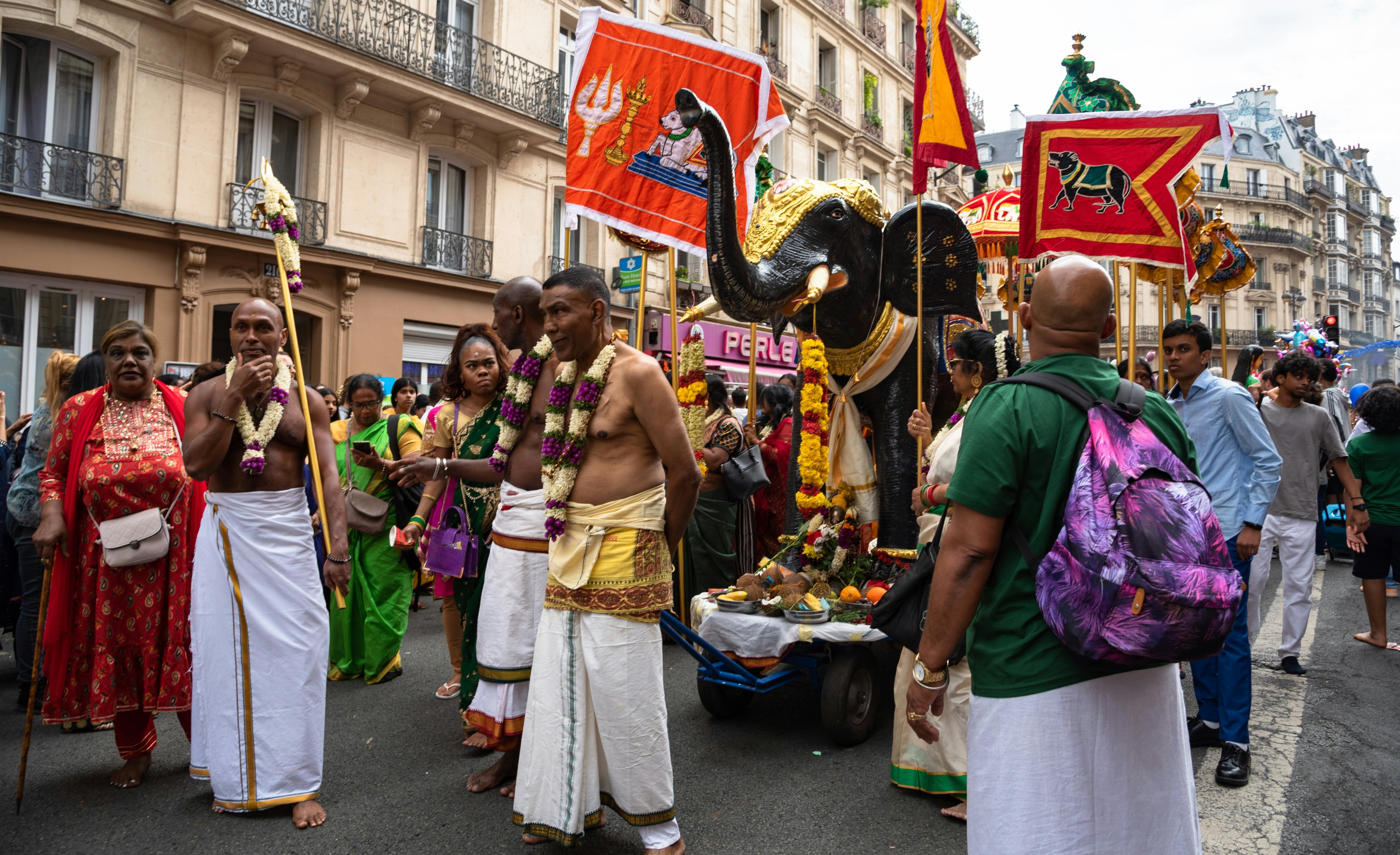 During a festival honoring the Hindu god Ganesh, men in sarongs and marigold necklaces accompany an effigy of an elephant (representing the deity) down a boulevard in Paris, France