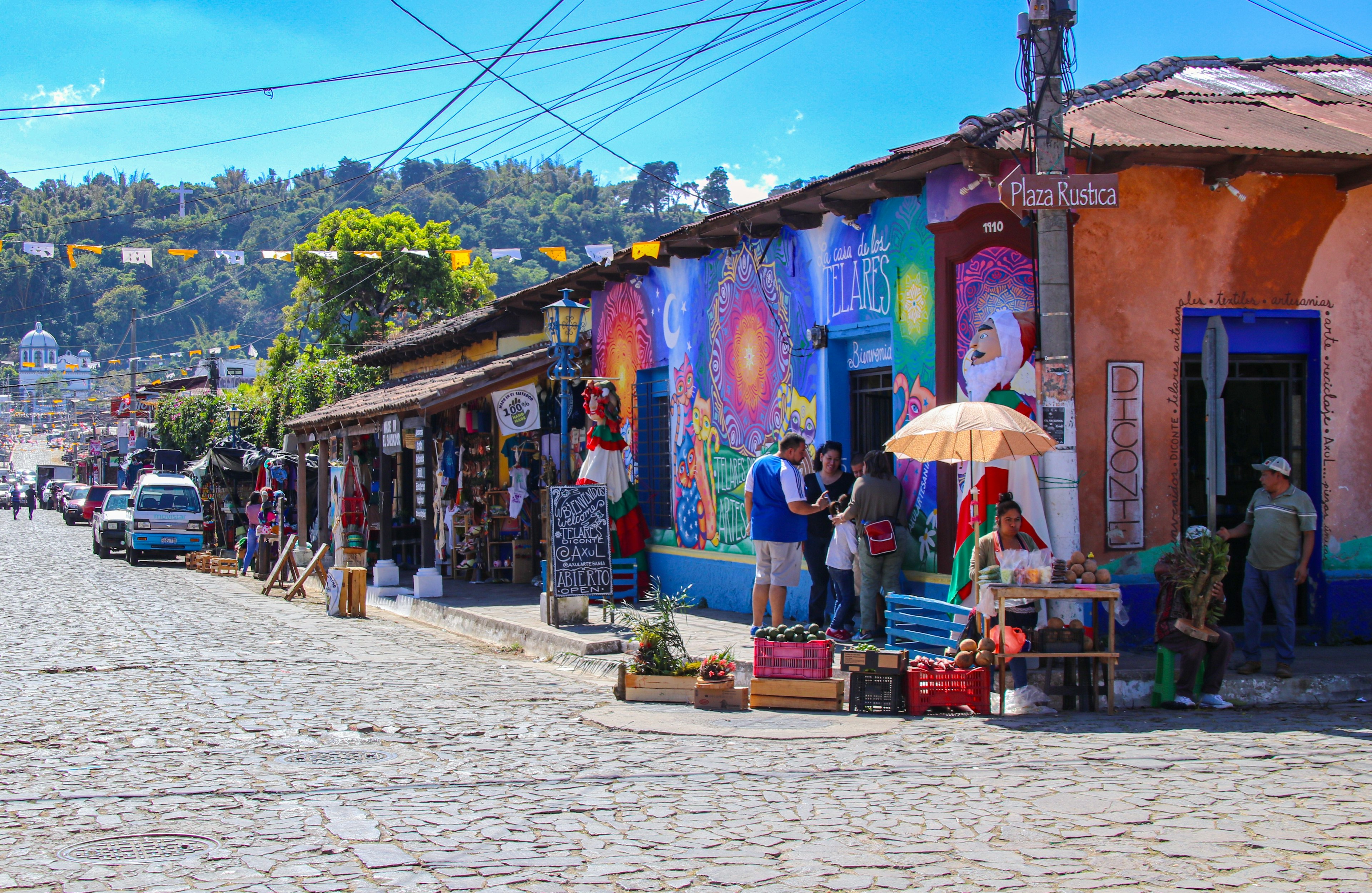 People shopping in a historic town with bright street art decorating the buildings