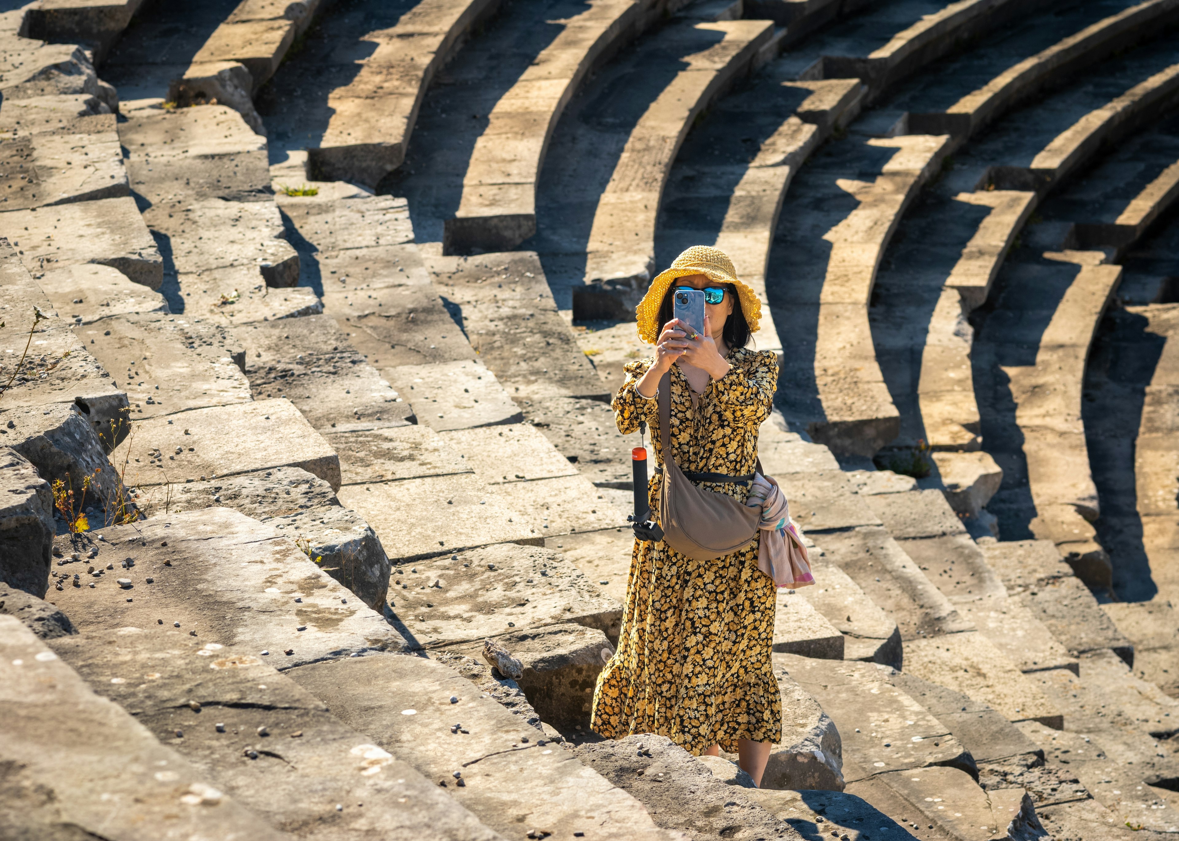 A woman takes a photo on her mobile phone as she visits the grand Roman amphitheater at Side in Antalya Province, Turkey (Turkiye)