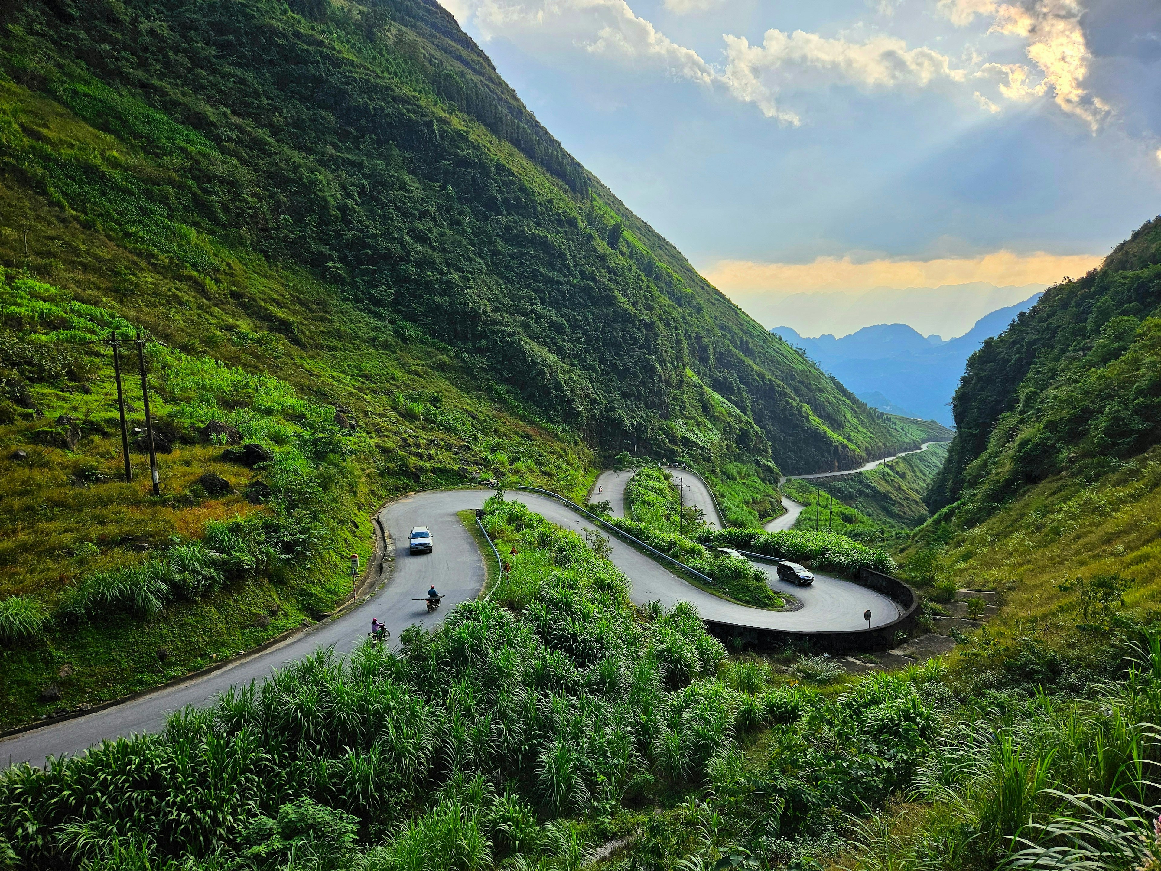 A view of winding switchbacks leading through a pass through steep green mountains