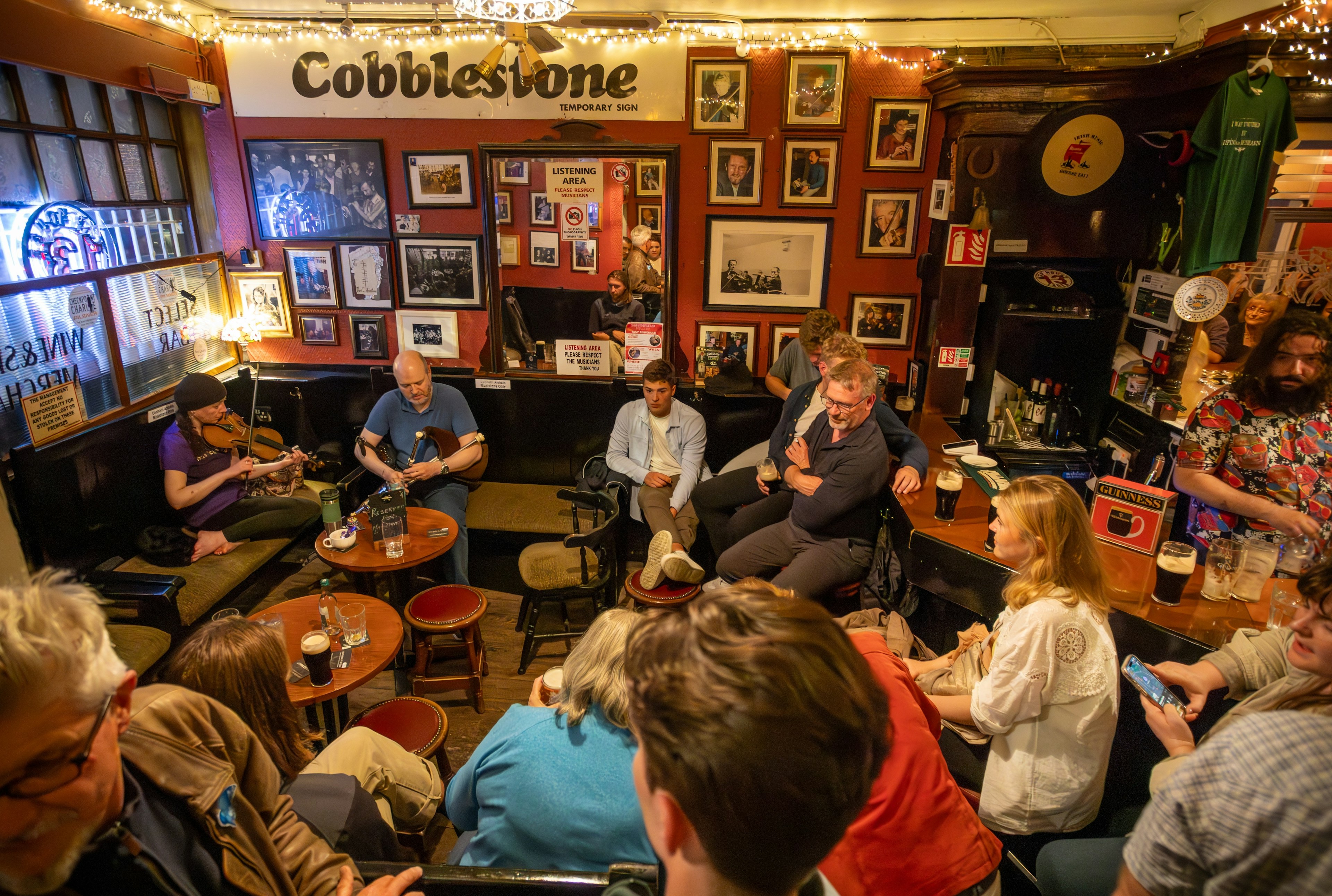 Two folk musicians play violin and bagpipes for visitors in Cobblestone.