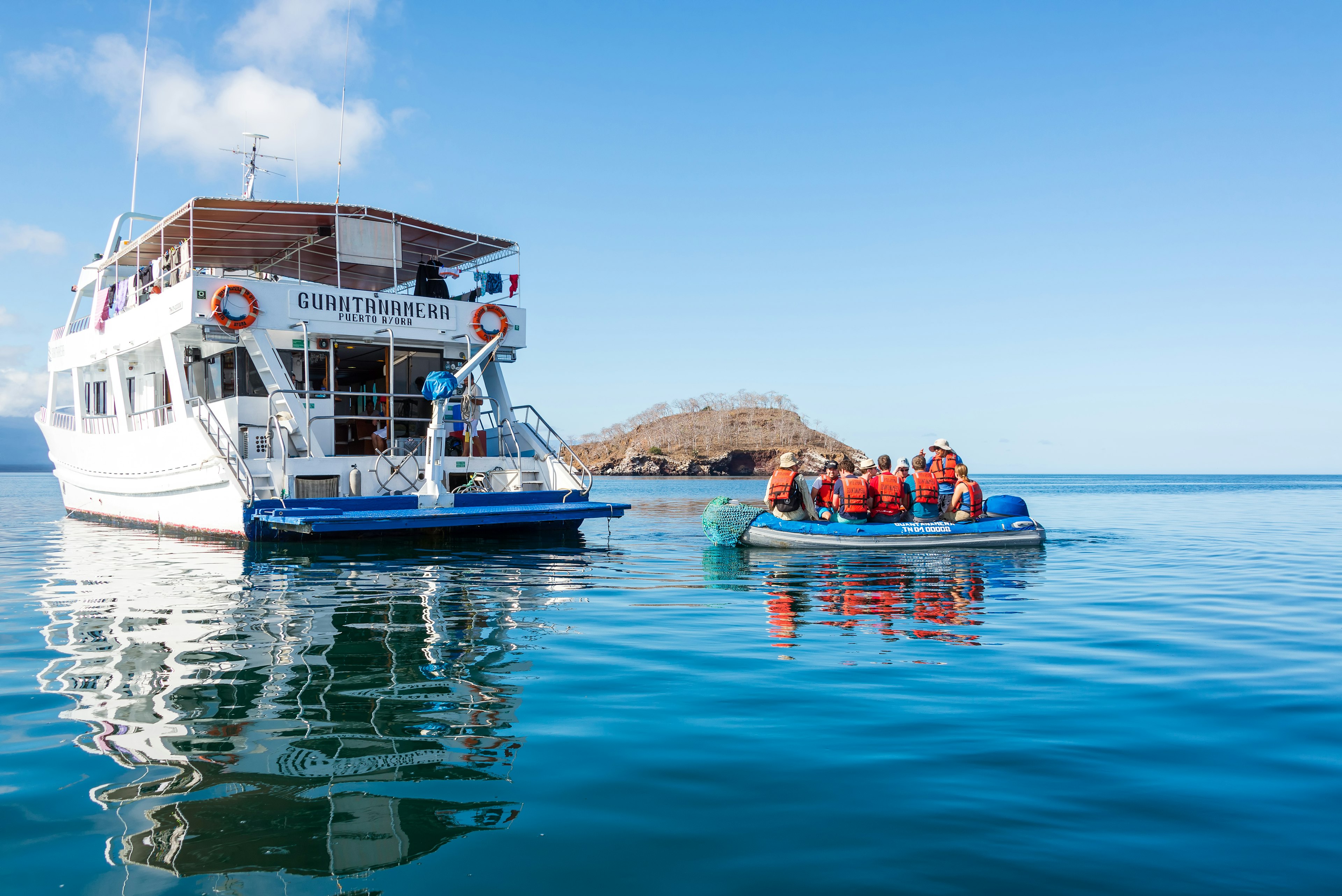 Tourists on a dinghy returning to a small cruise ship in a harbor in the Galápagos Islands, Ecuador