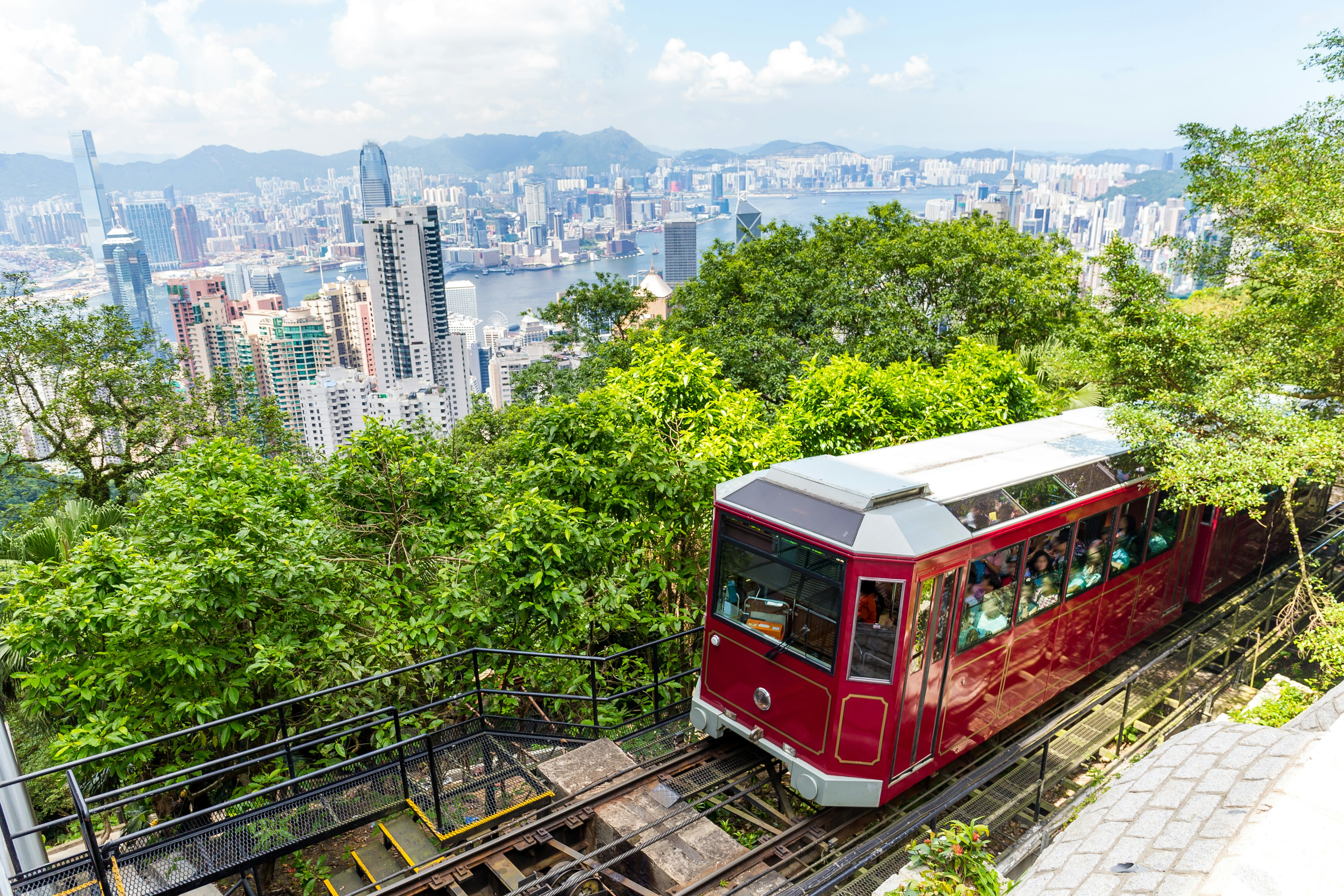 A red tram heads up to a viewpoint over a city skyline