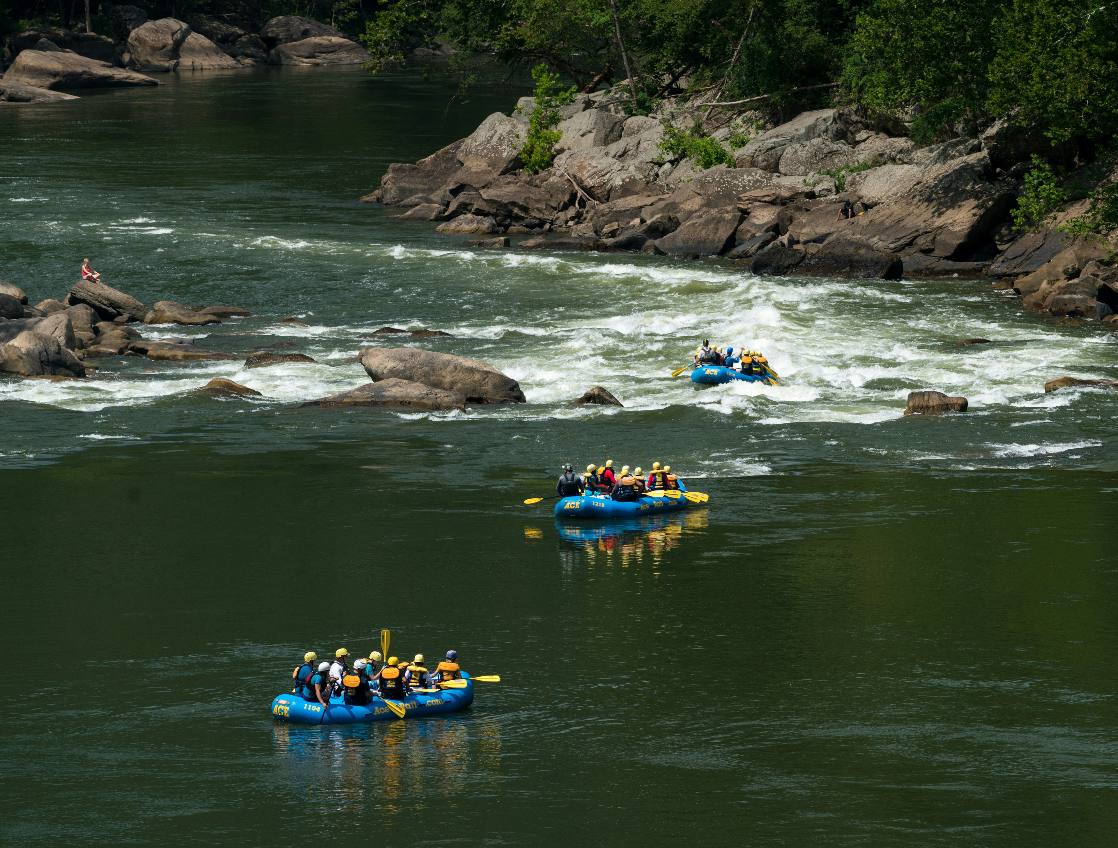 Rafters float towards the rapids under the high arched New River Gorge bridge in West Virginia.