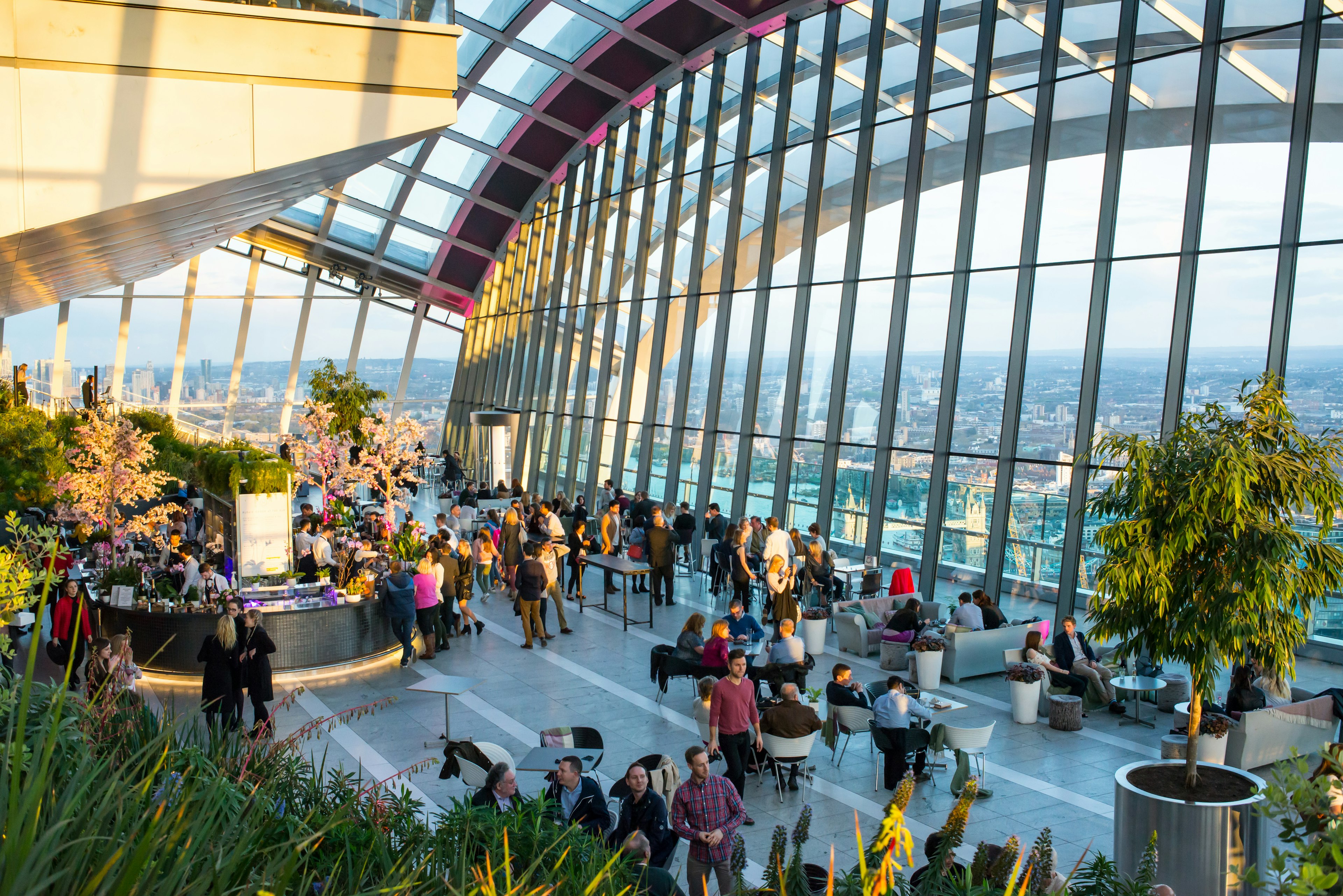 People at a cafe within a large glass skyscraper enjoying city views.