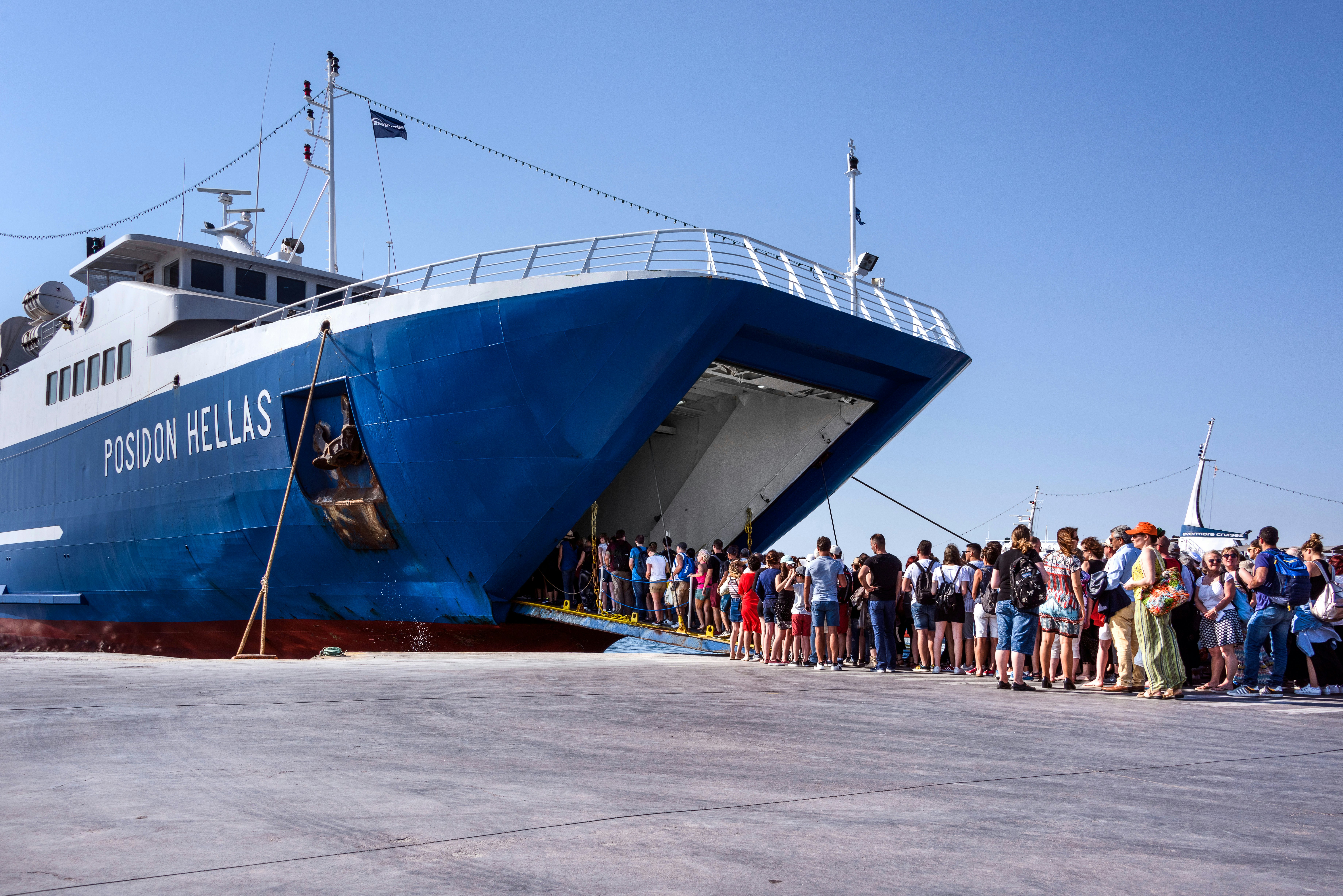 A crowd of people board a large ferry at the Aegina port.