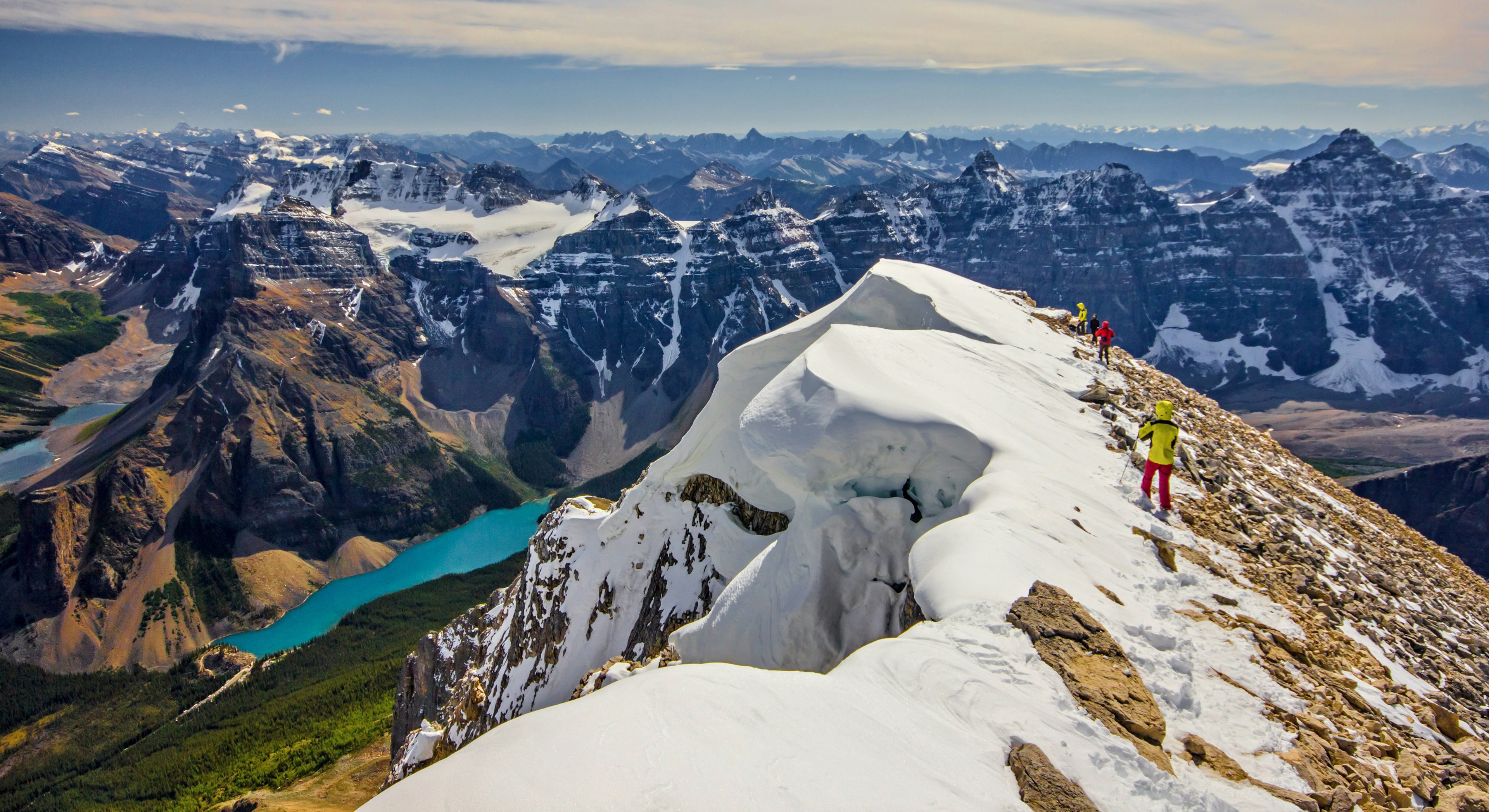 Mountain climbers reach a snowy peak in Canada.