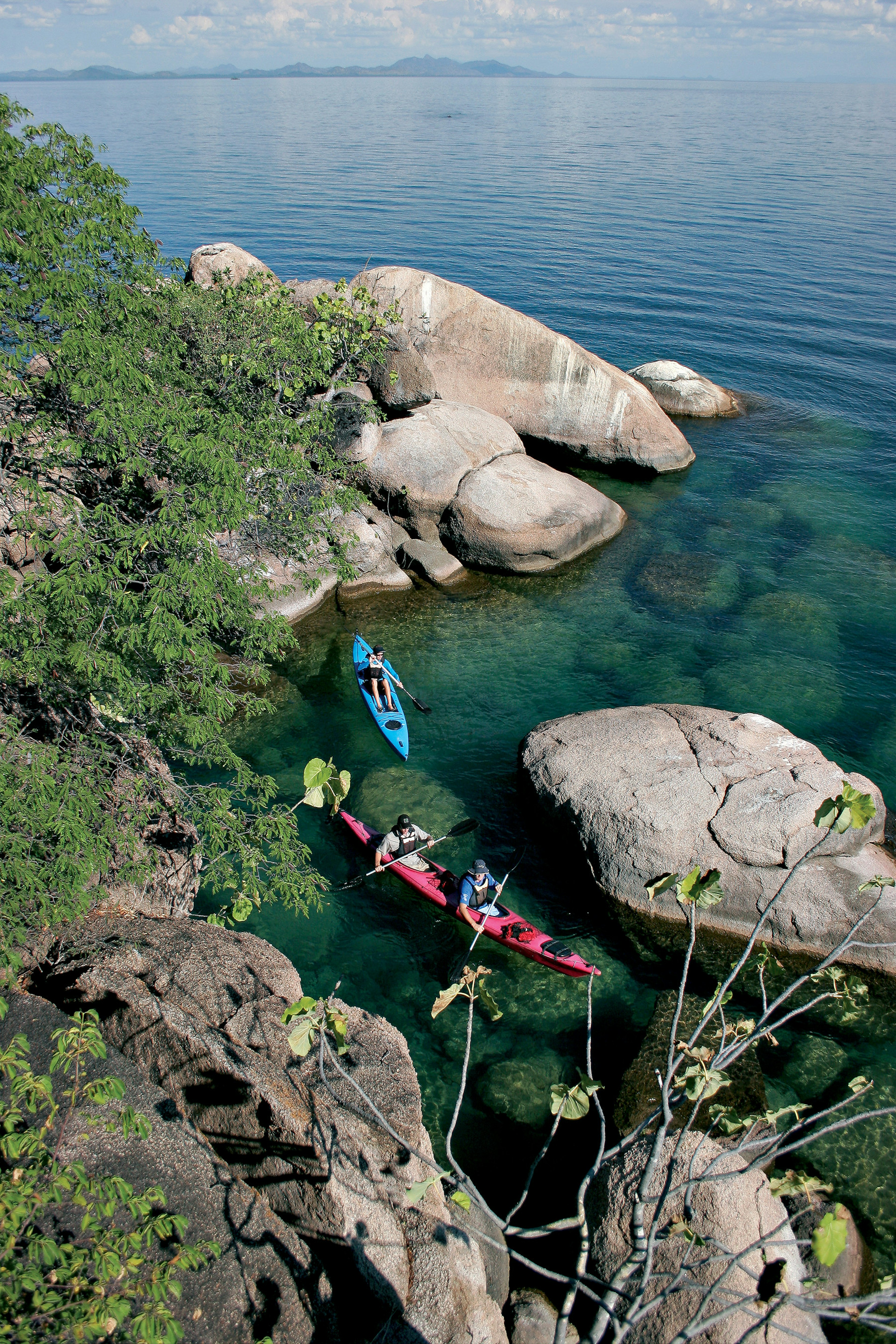 Paddlers explore the scenic rock formations of the islands of Lake Malawi, Malawi, Africa.