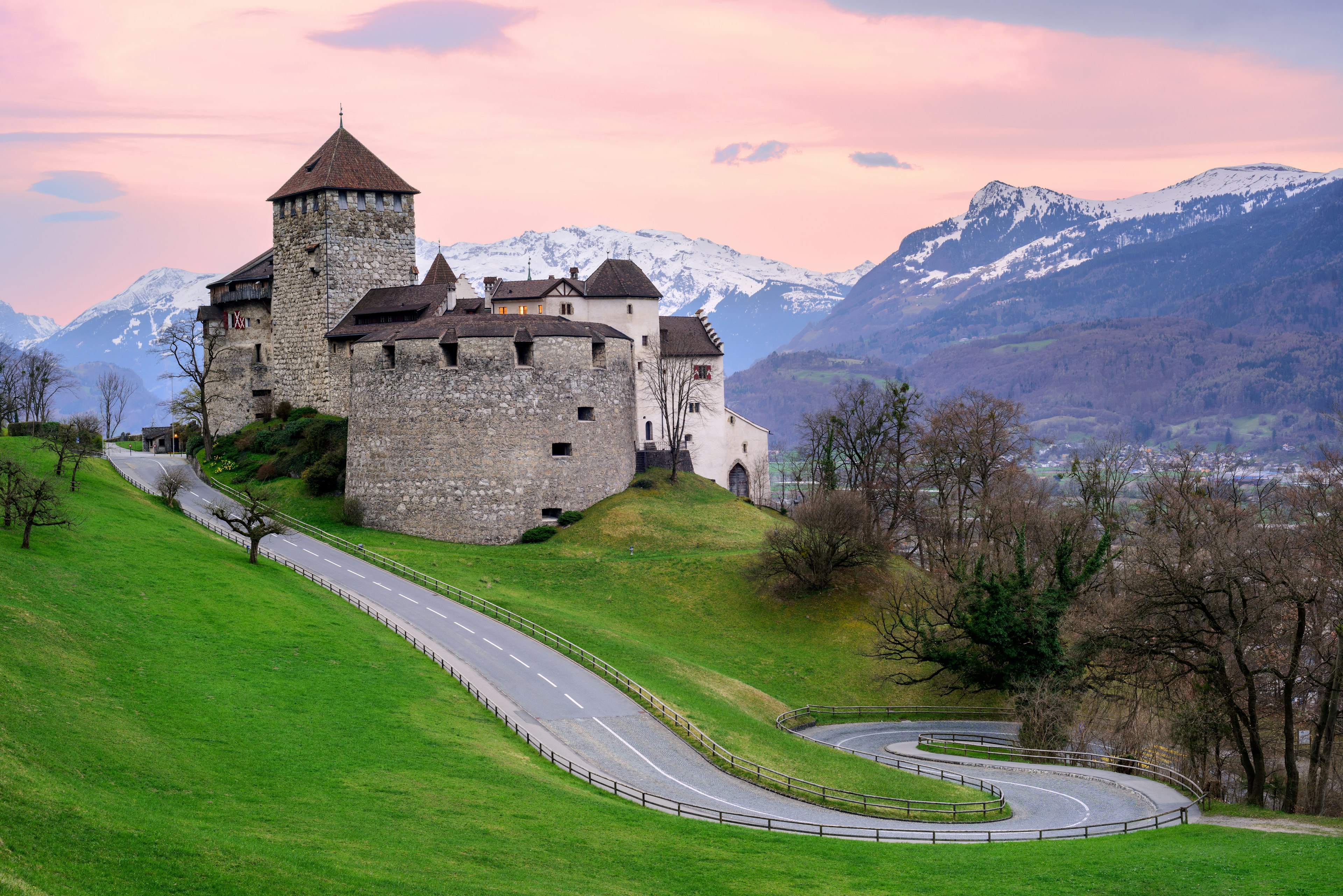 Vaduz Castle, the official residence of the Prince of Liechtenstein, with snow covered Alps mountains in background on sunset.