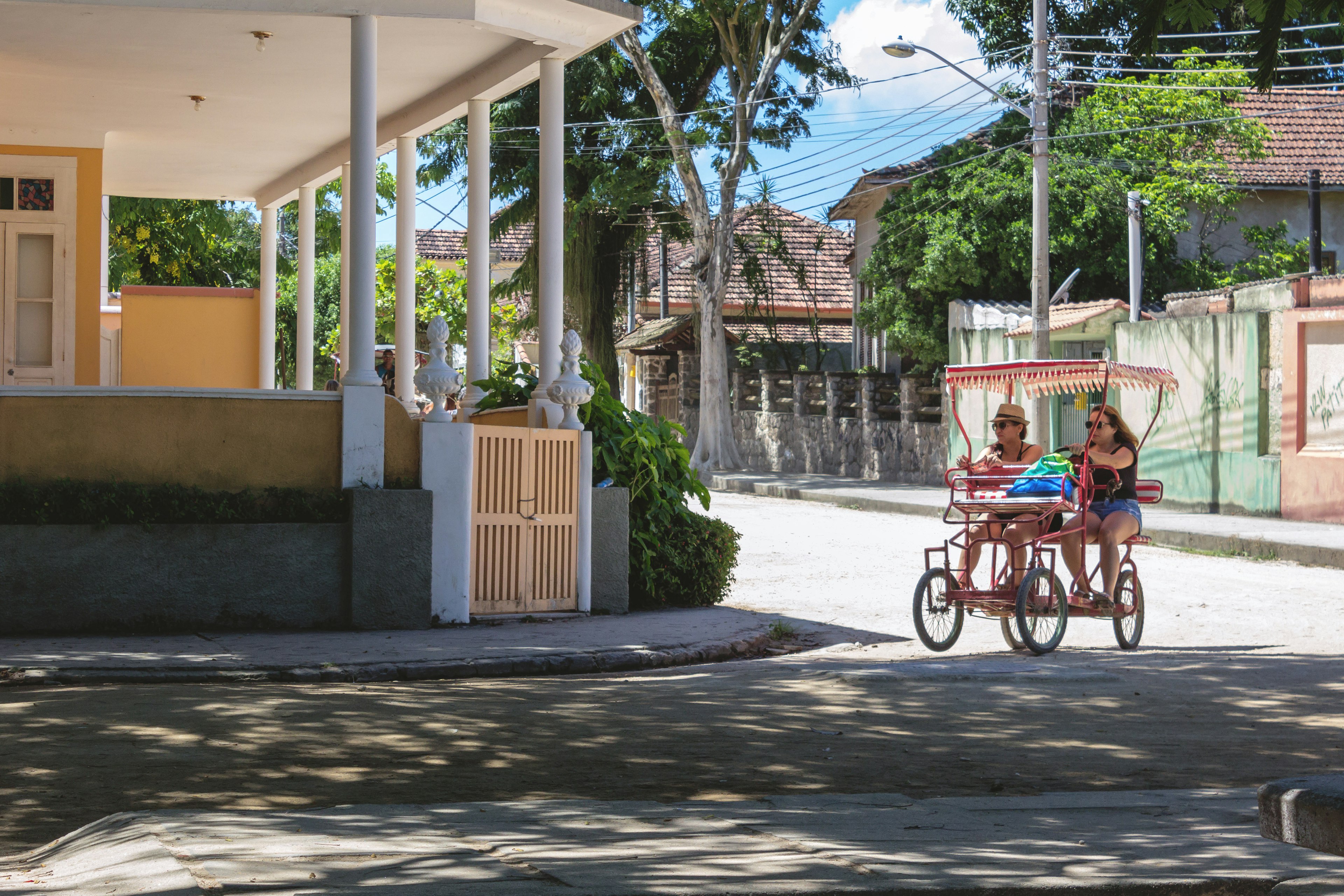 Two females travelling on a surrey bike on the street in Paqueta Island.