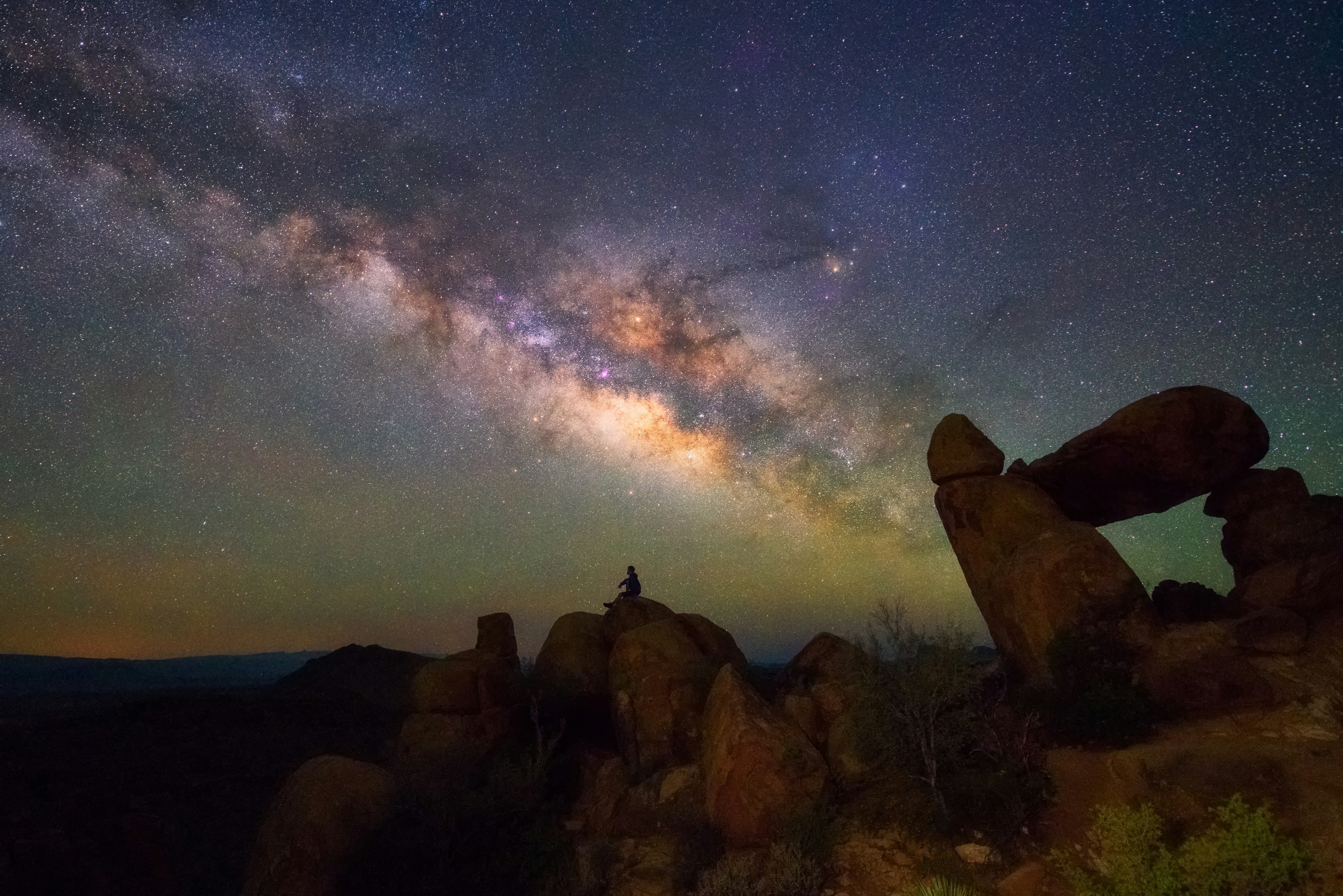 Human observing Milky way at Balanced Rock, Big Bend National park, Texas USA.