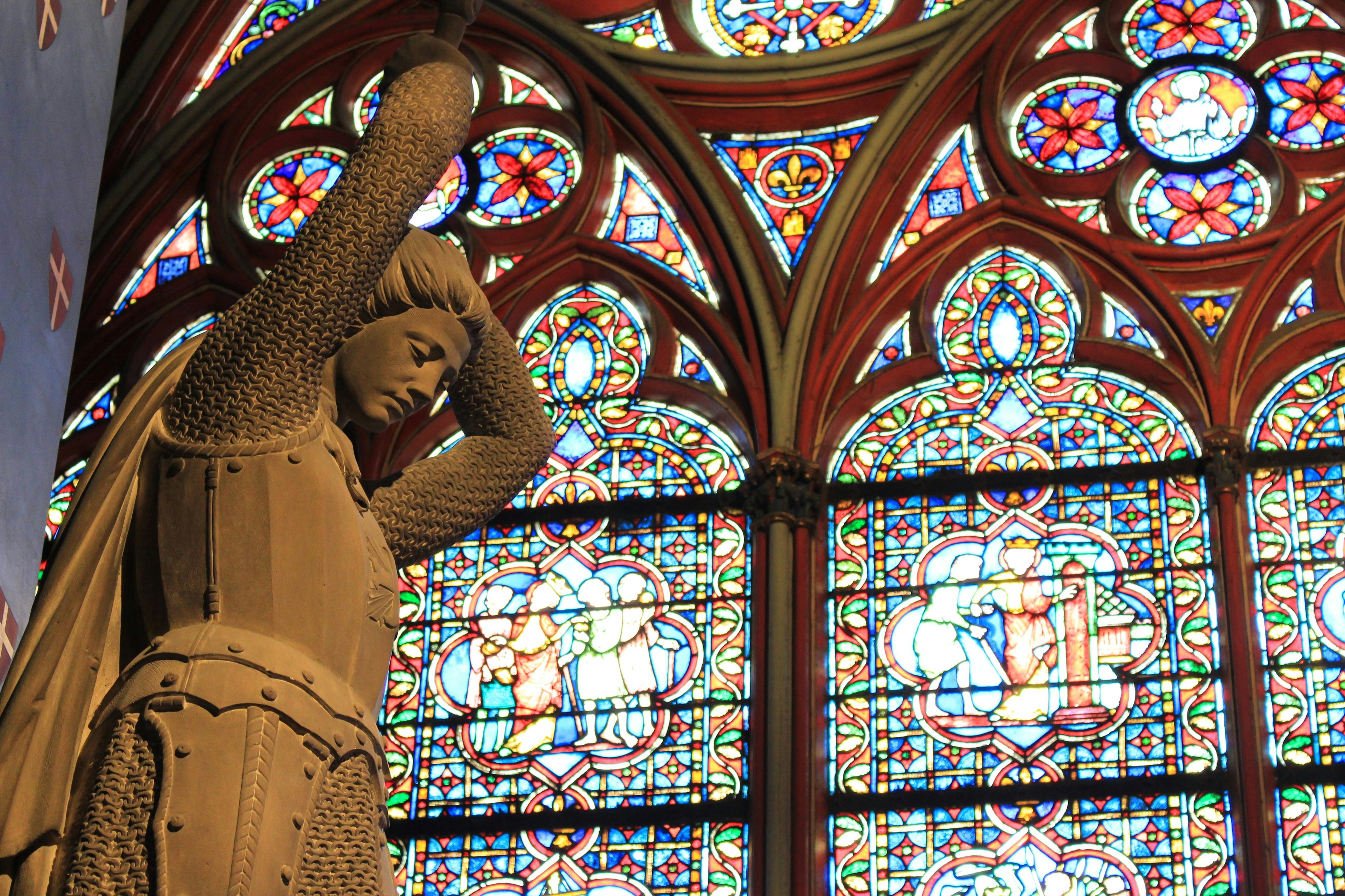 A statue and a stained glass window inside the Notre Dame Cathedral in Paris