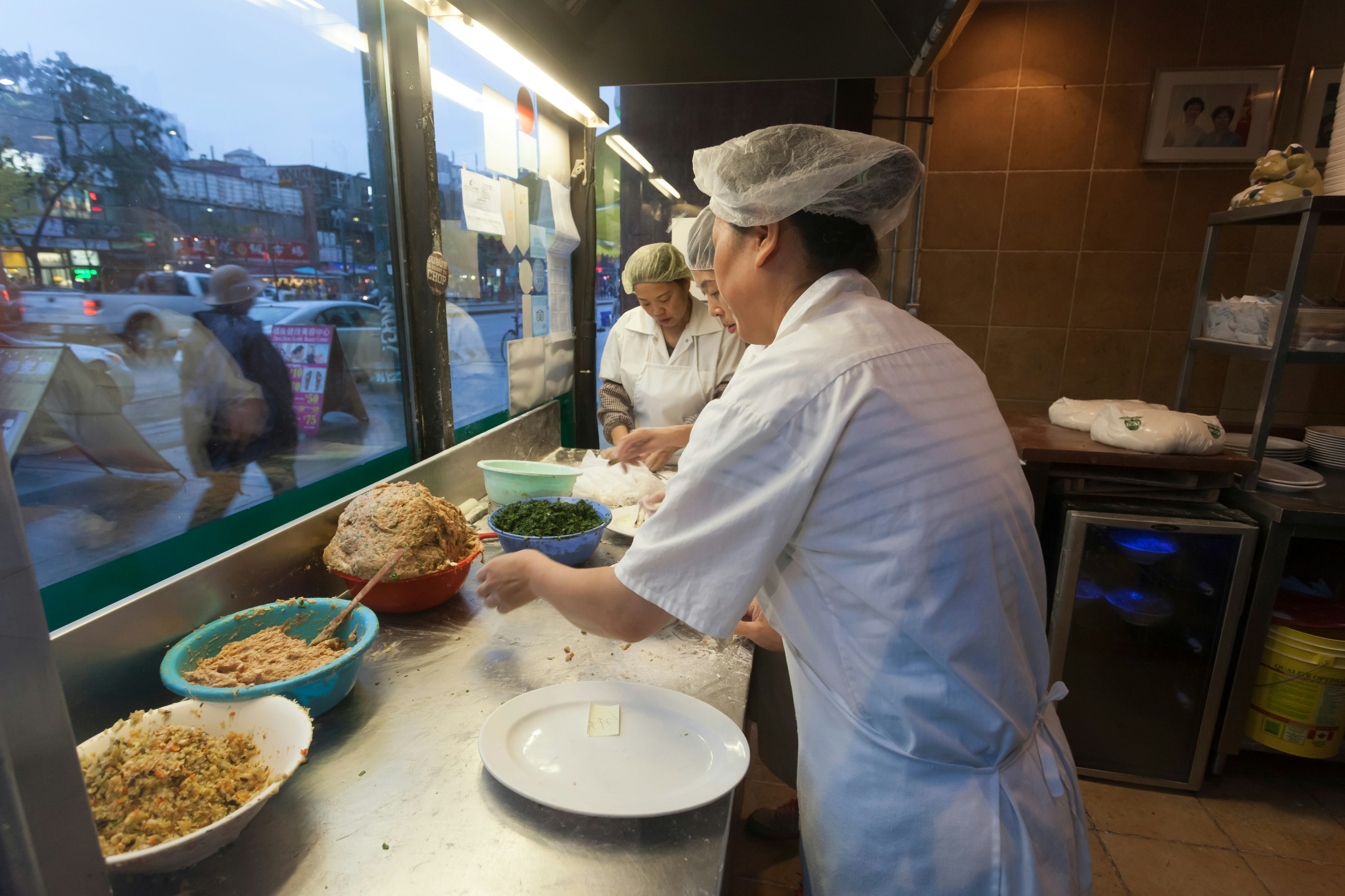 Women preparing traditional dumplings at the front window of a Chinese restaurant in China town.