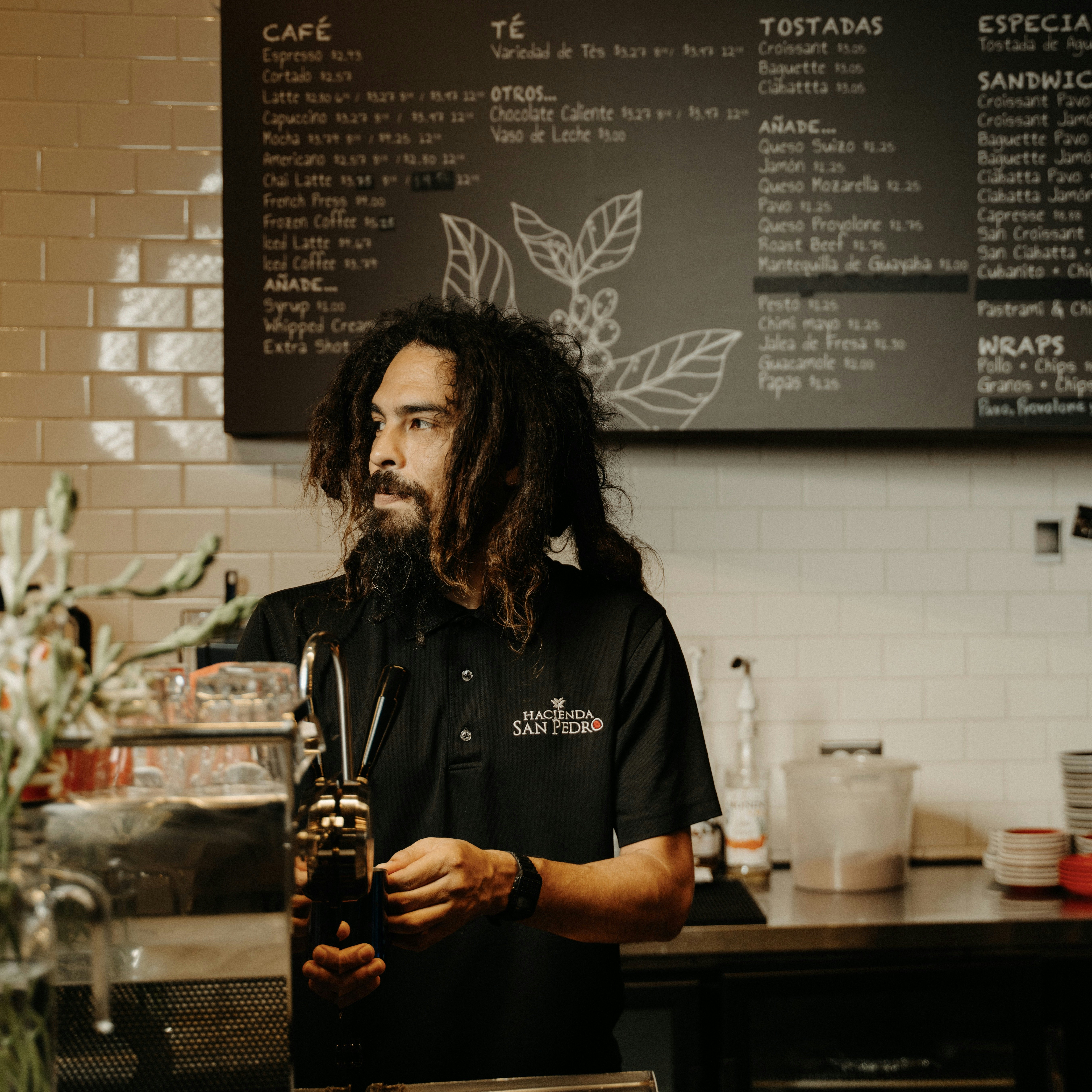 A man with locs stands behind the counter of a coffee bar in San Juan, Puerto Rico