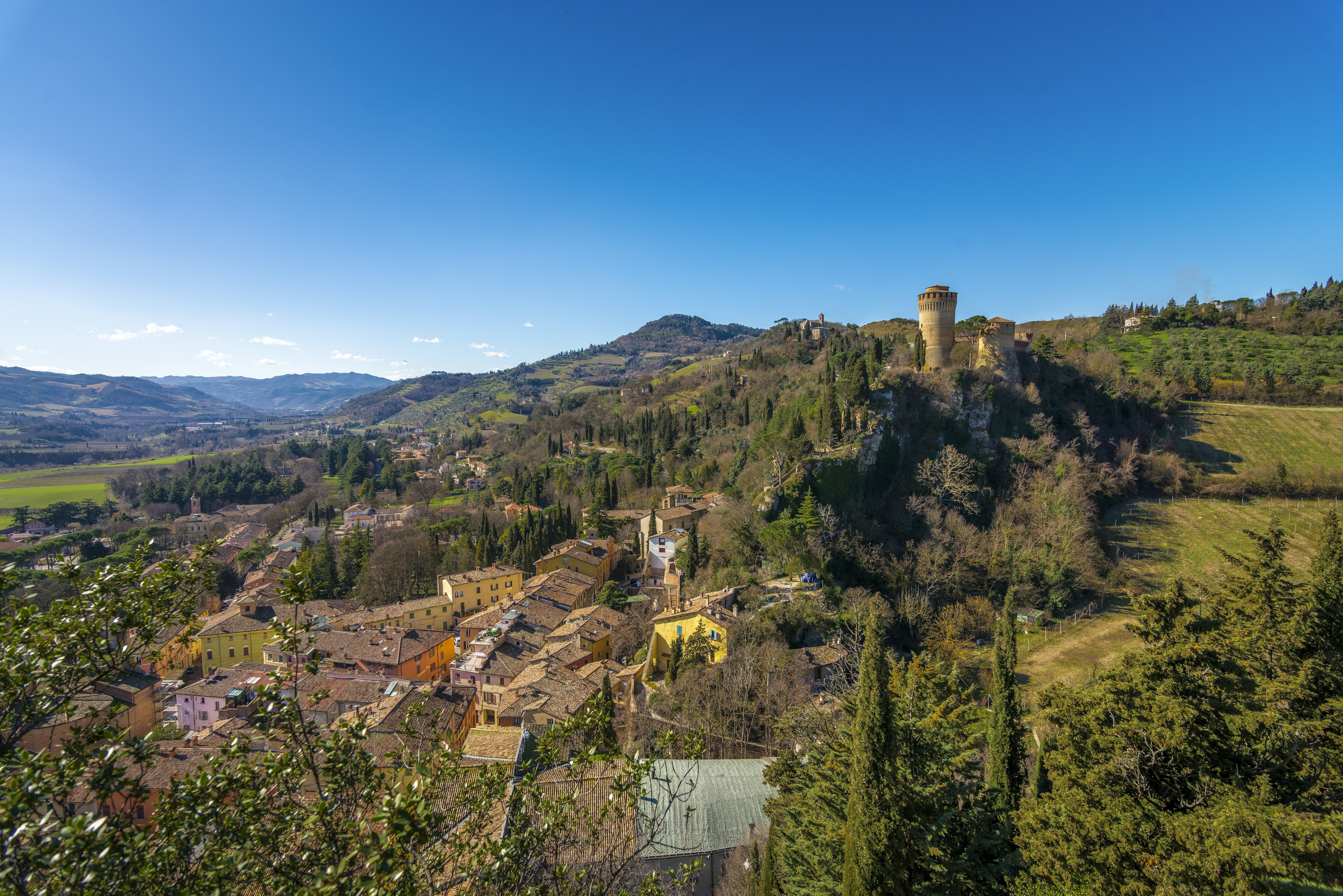 Aerial shot of the hilltop town of Brisighella surrounded by green hills.