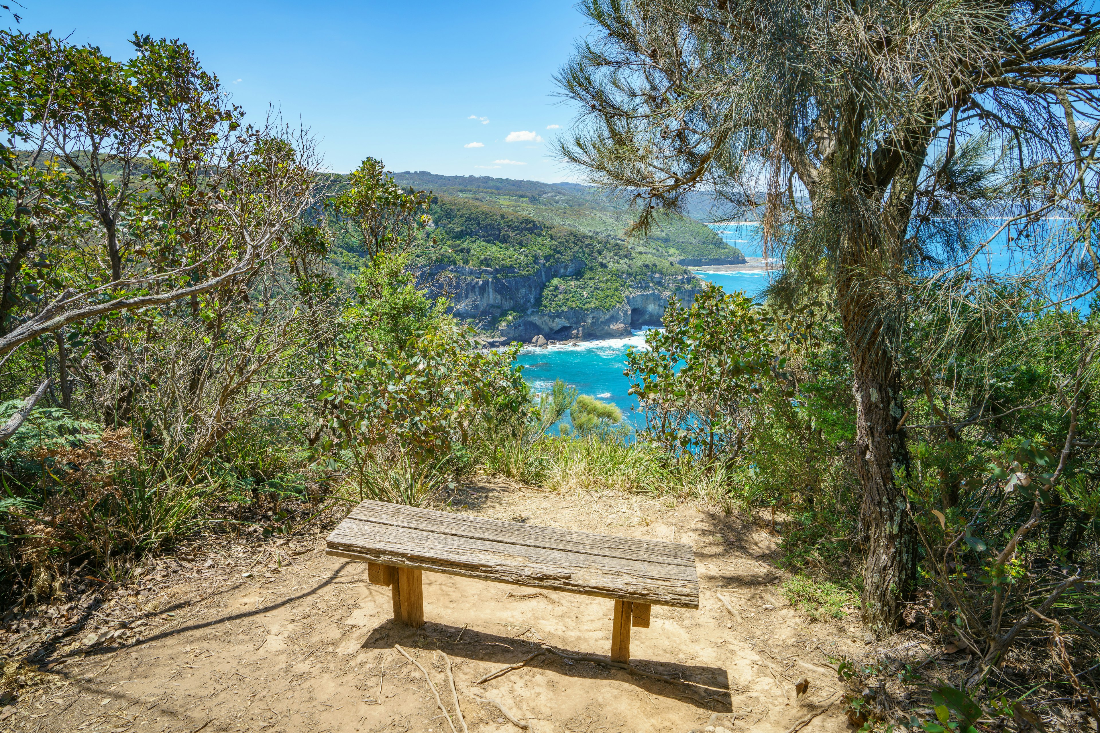 A wooden bench at a lookout from a clifftop over the ocean