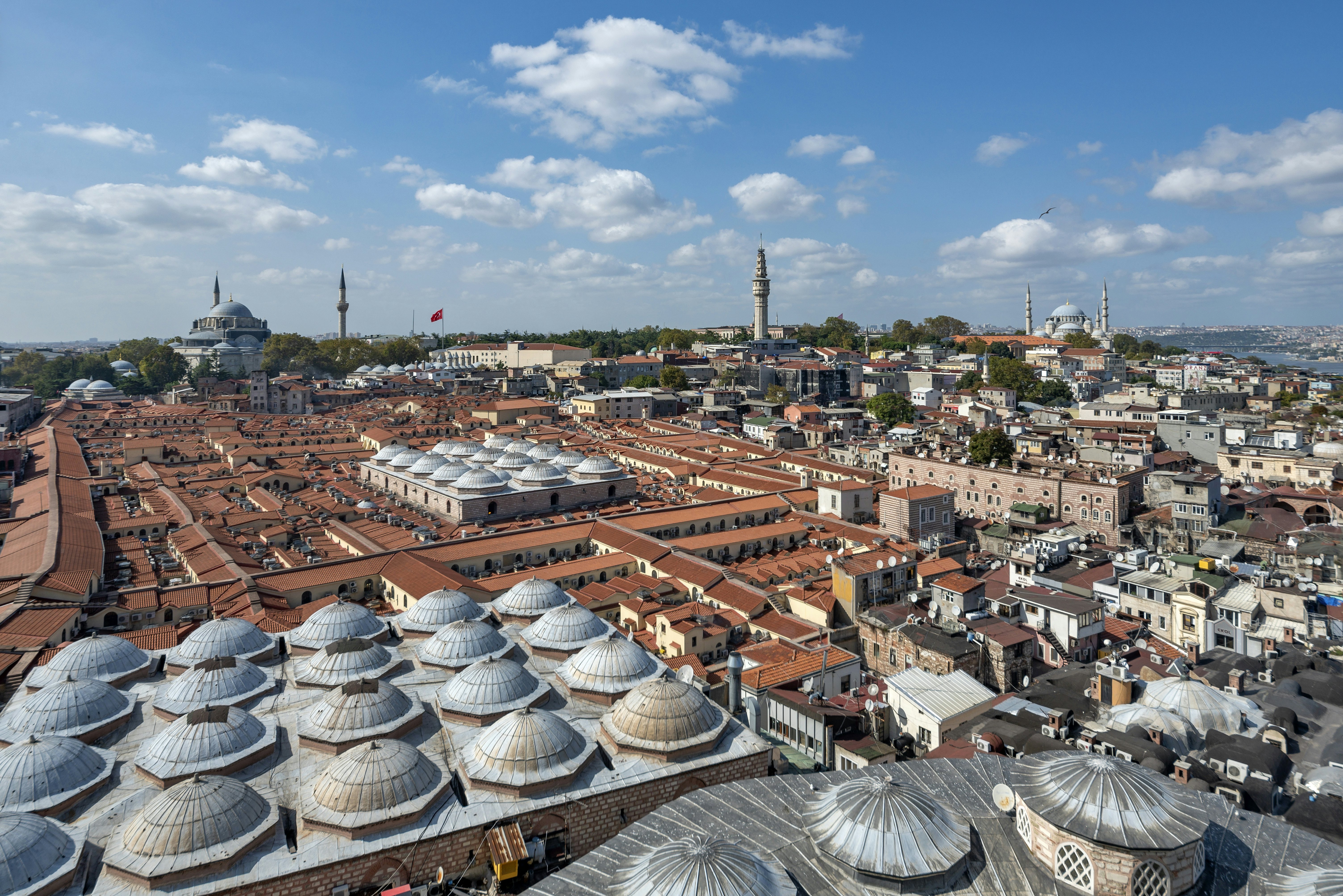 A red-roofed covered market takes up a huge space in a built-up city with mosques and minarets in the distance