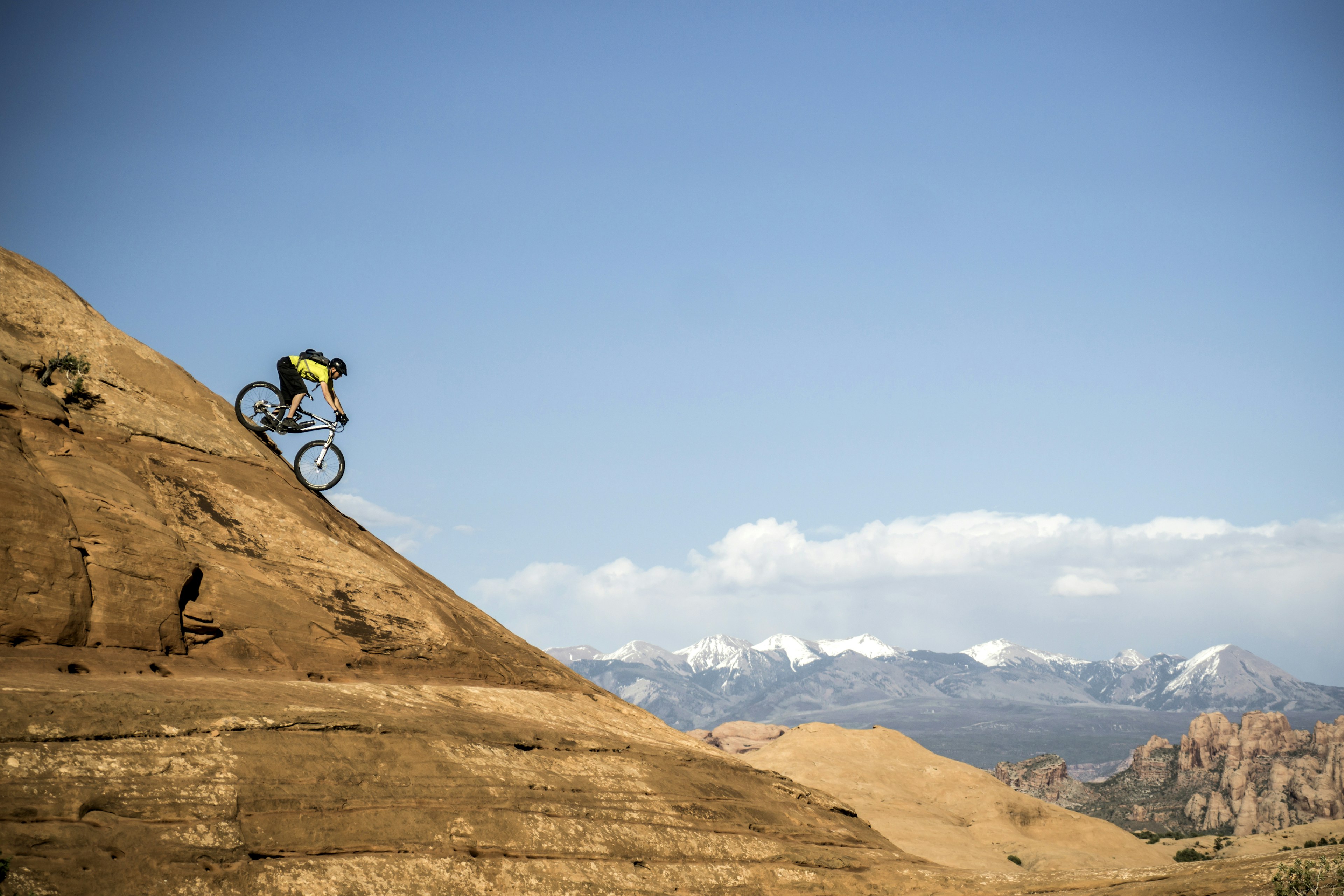 A man mountain-biking down a steep mountain track