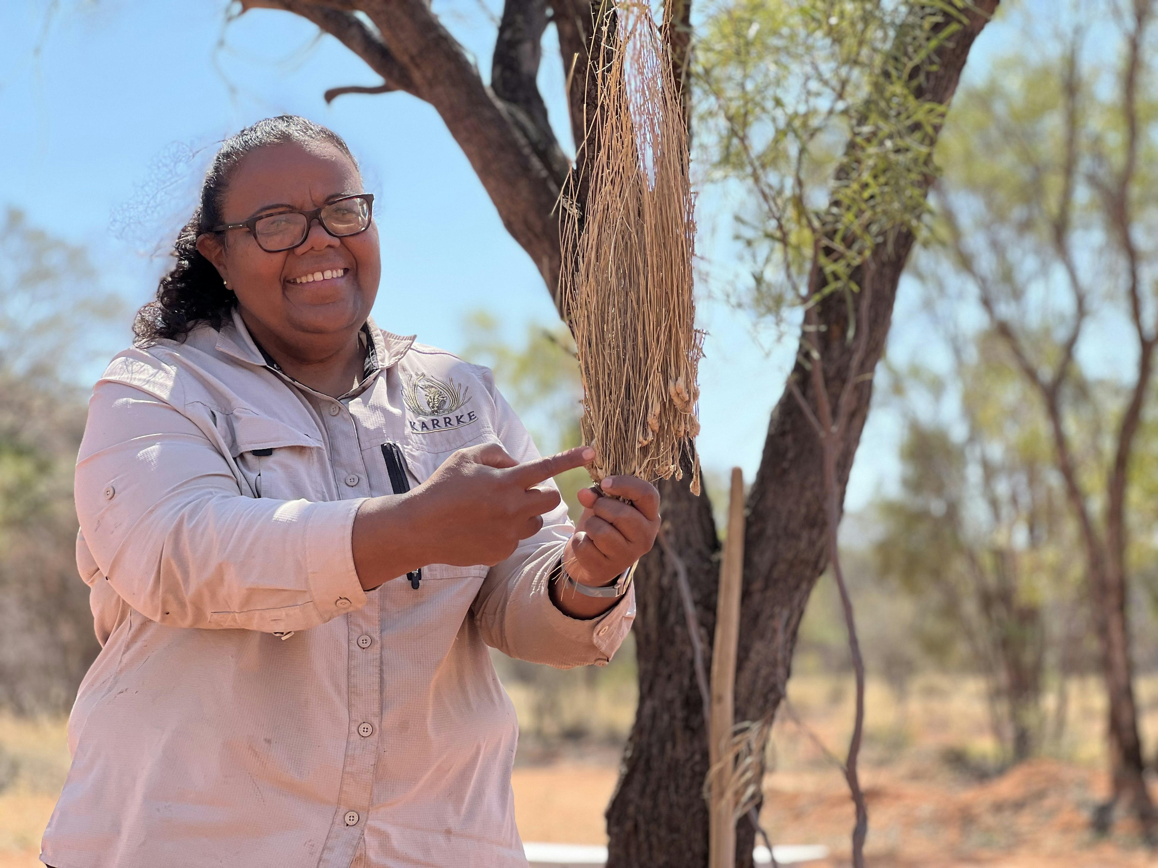 An Aboriginal woman leading a tour smiles as she points to some Tours near Watarrka National Park.