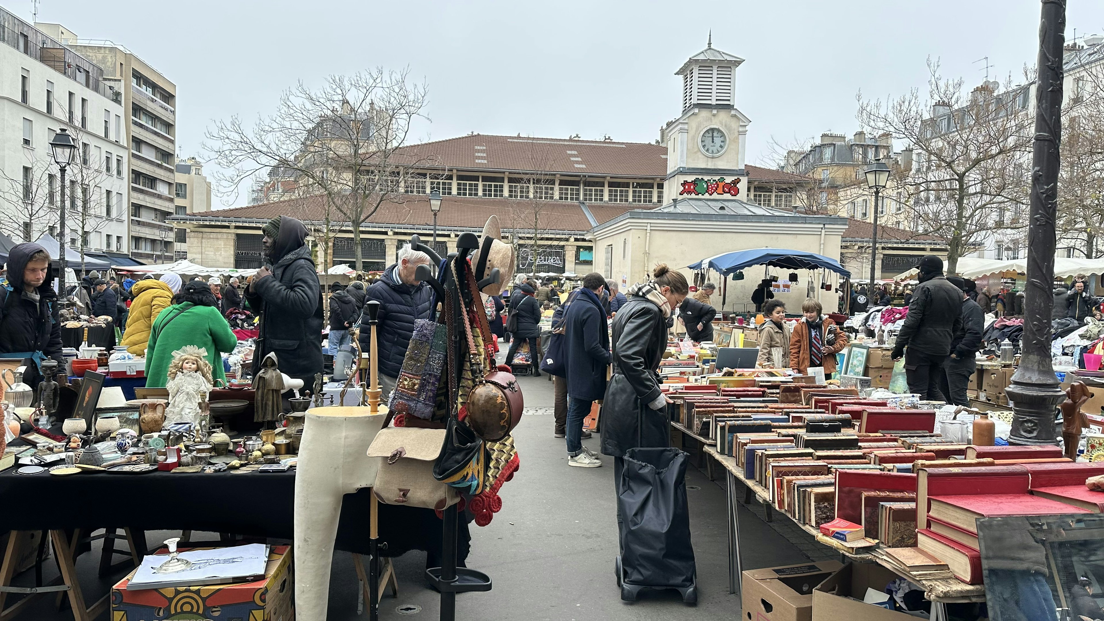 Shoppers browse stalls full of books and antiques at an outdoors market