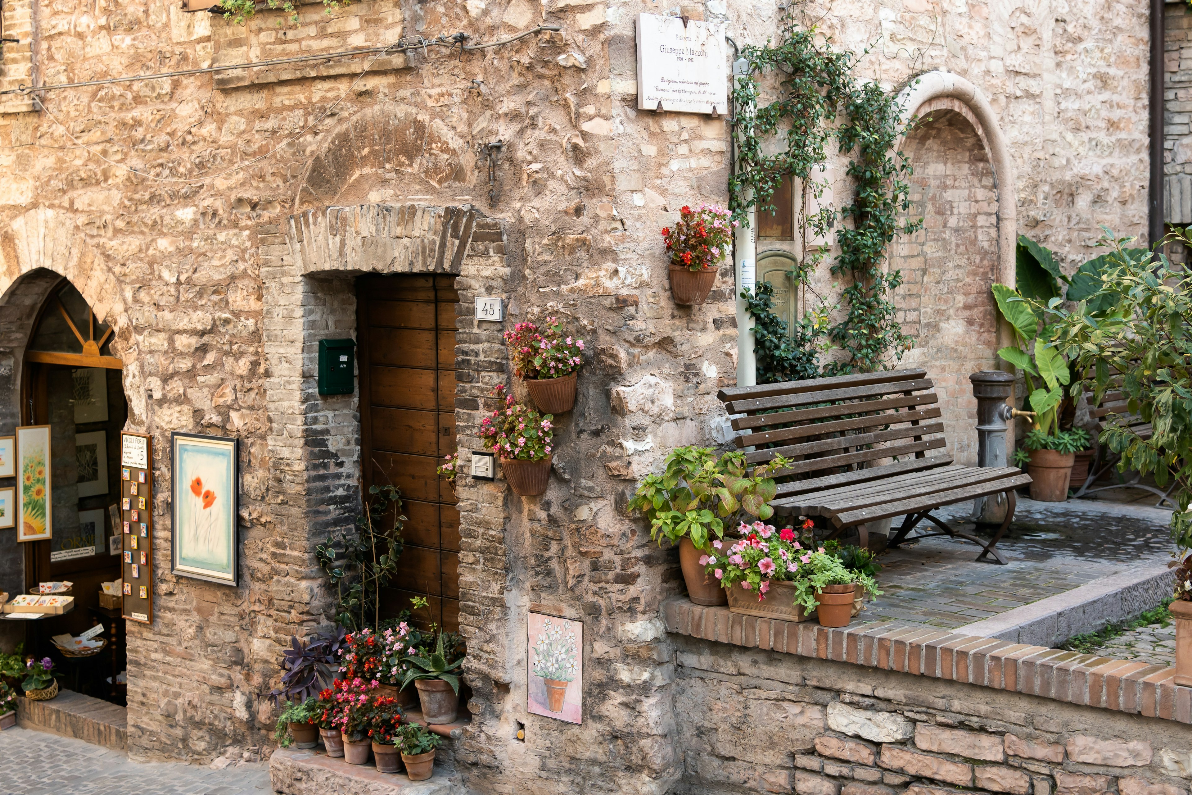 A medieval stone building adorned with flower baskets and hanging vines.