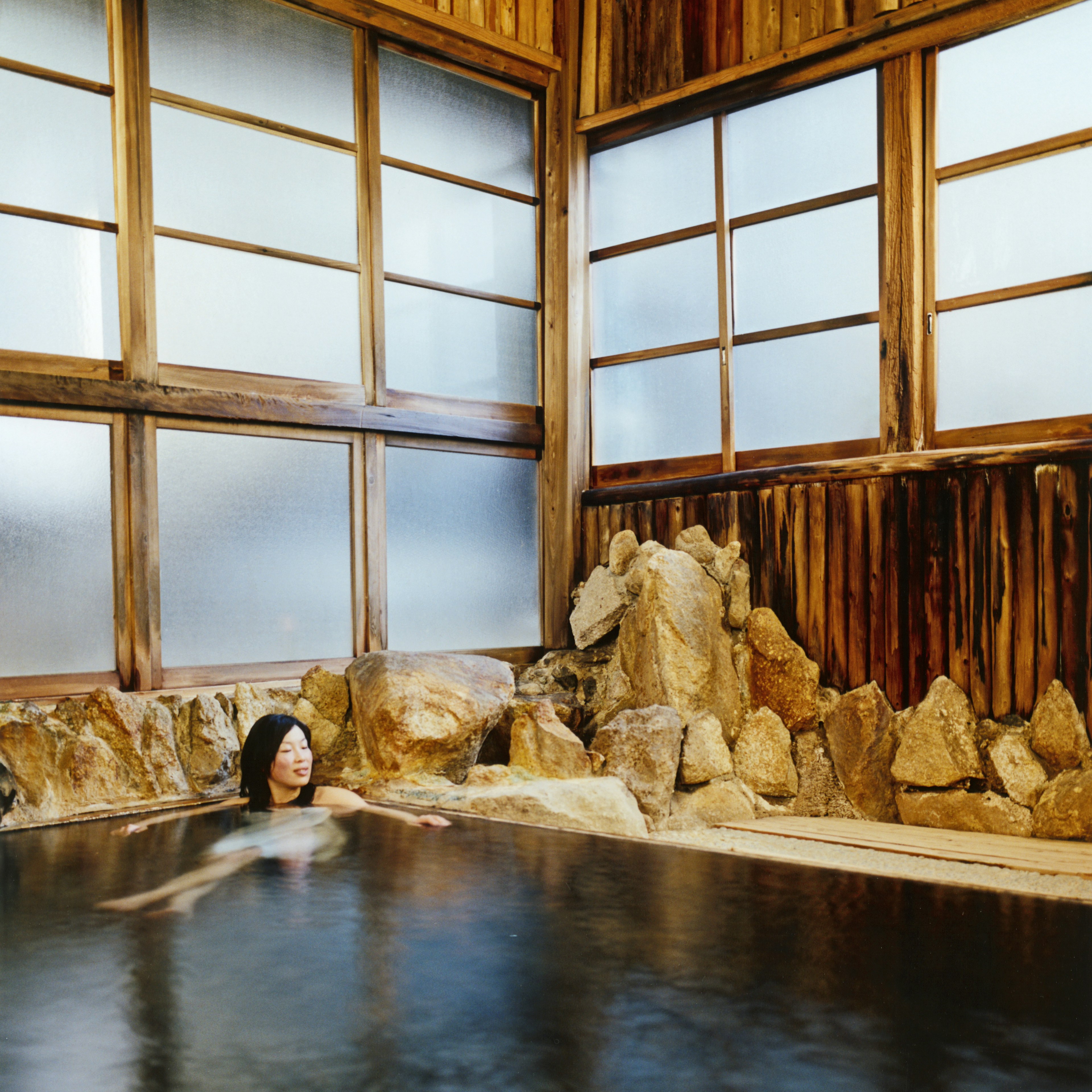 Woman soaking in a wooden onsen at Adumaya Ryokan in Yunomine, Japan.