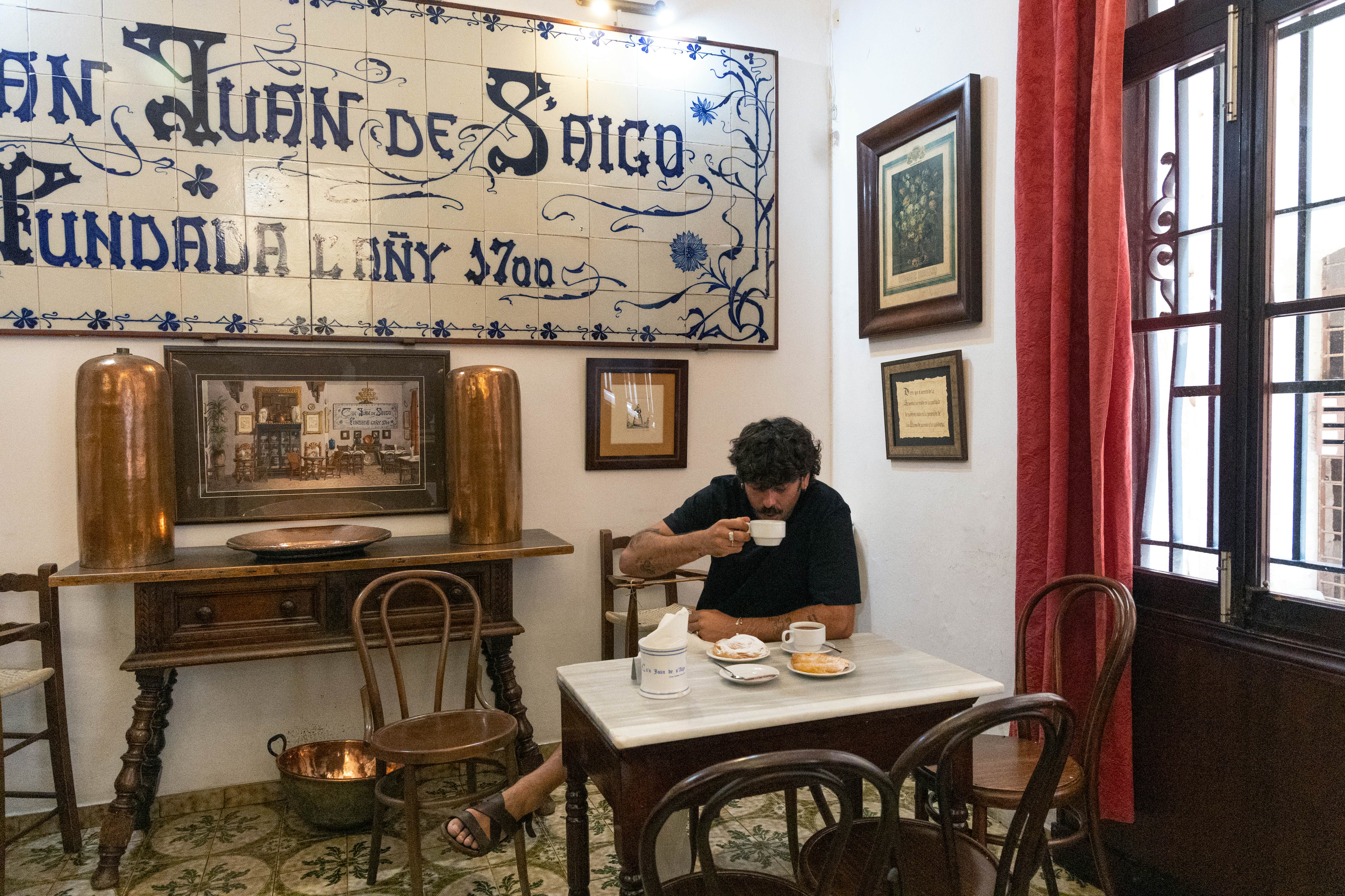 Man drinking from a teacup, surrounded by traditional décor in a Spanish cafe