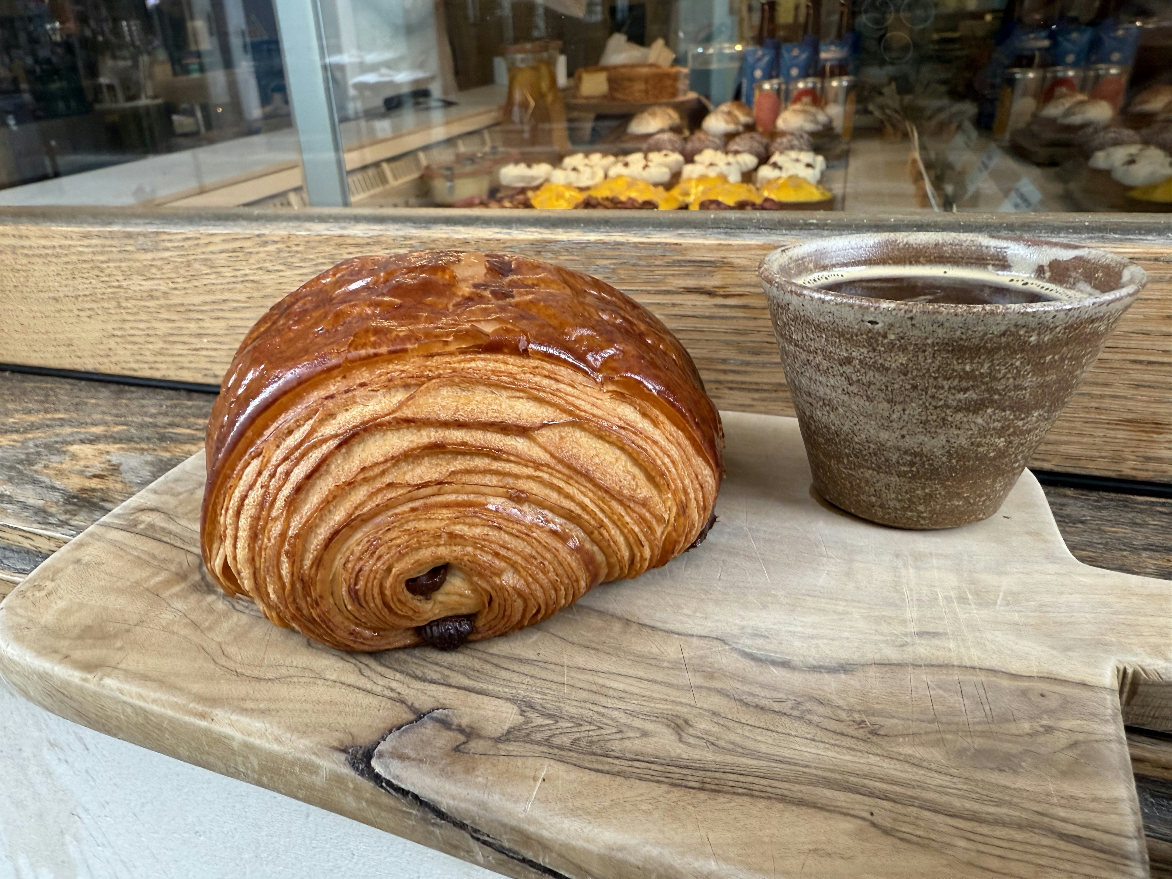 A pain au chocolate with coffee, outside a bakery in Paris.