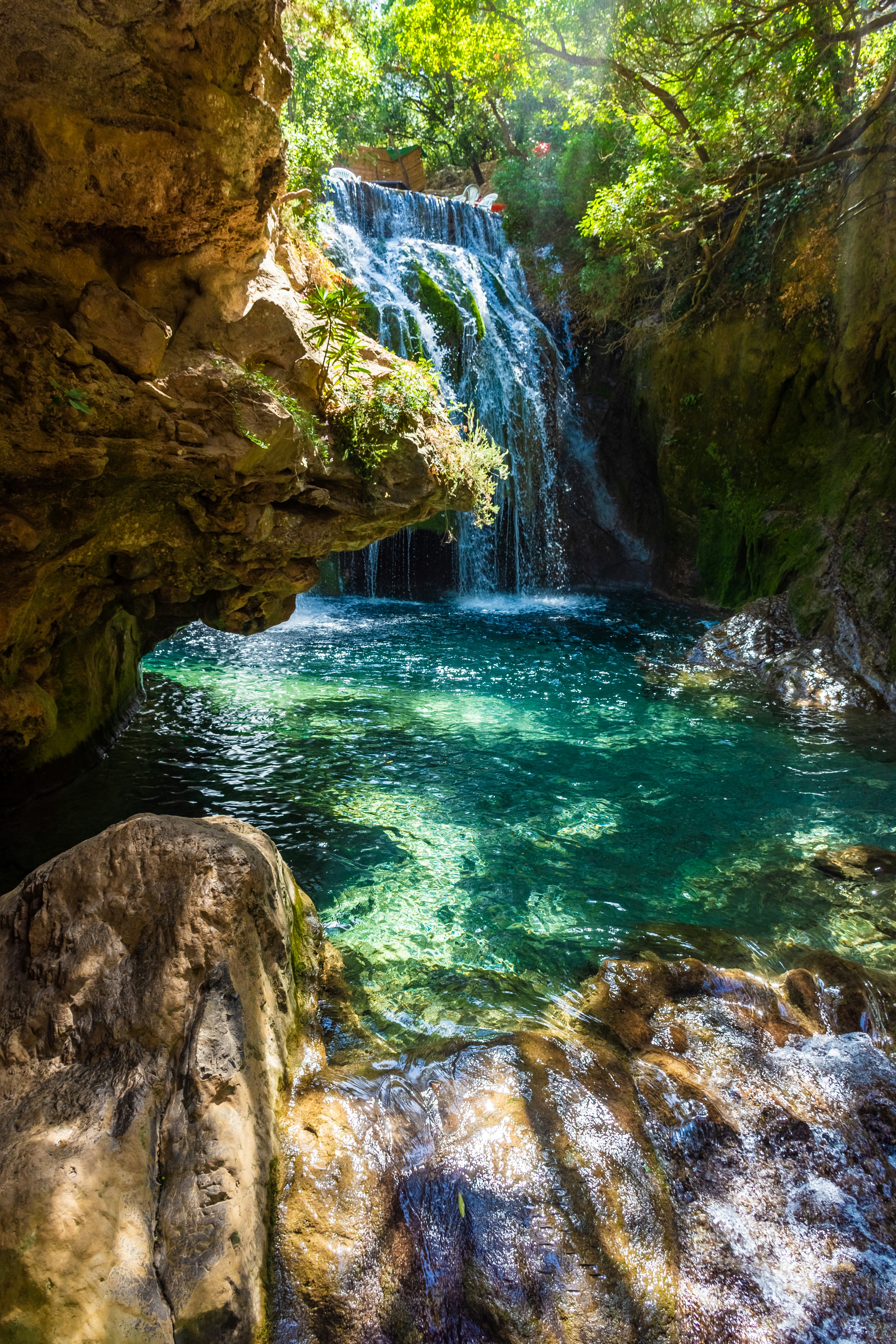 Waterfall of Akchour, Talassemtane National Park, Morocco with dappled sunlight on rocks in the foreground