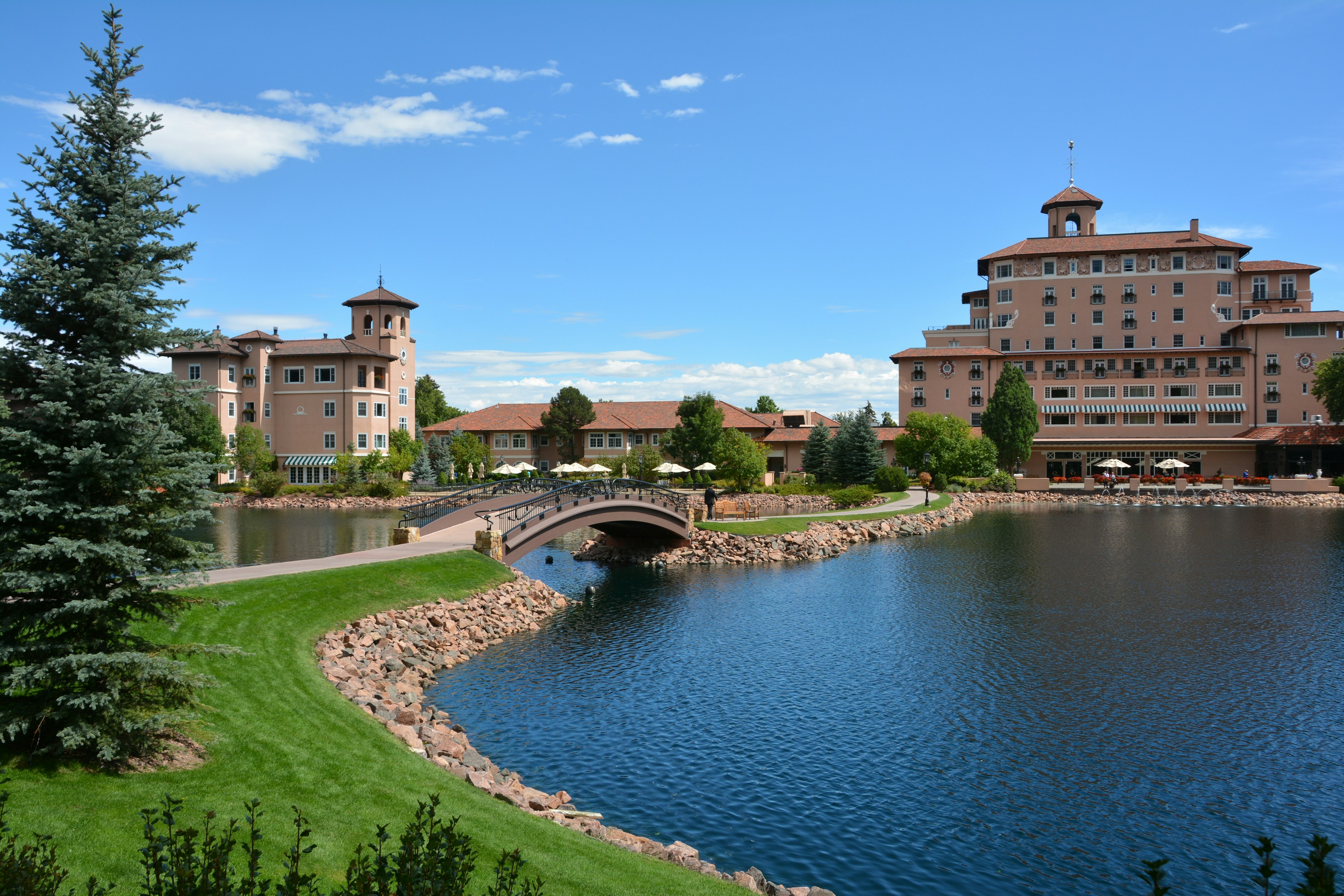 Two Hotel Buildings Forming a Luxurious Resort Are picture in Front of a Man-Made Pond Spaned by a Bridge